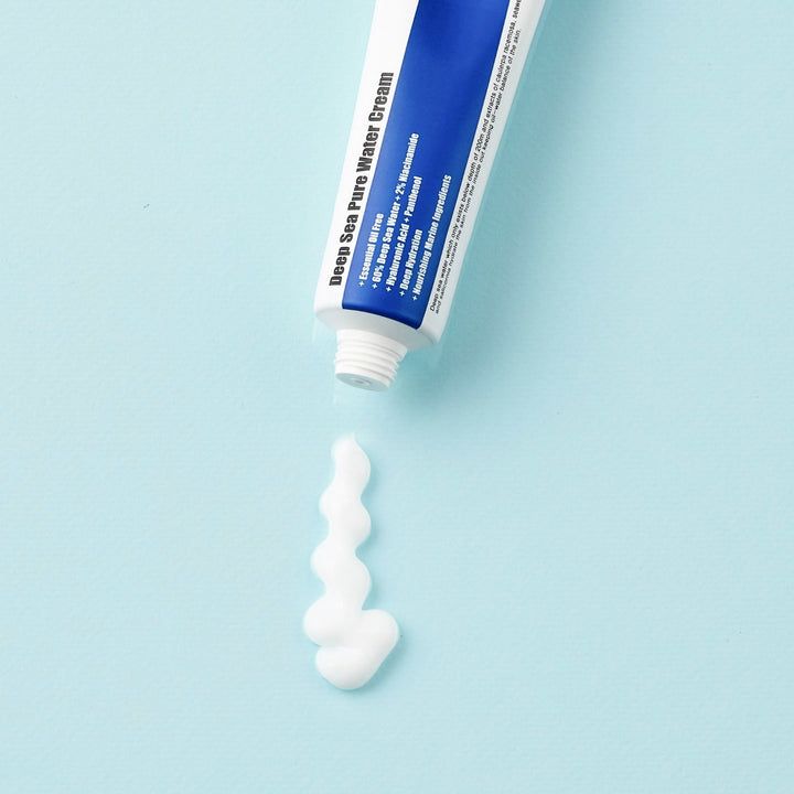 Weiße Creme kommt aus einer Tube. Der Text auf der Tube ist Deep Sea Pure Water Cream. Der Hintergrund ist hellblau.