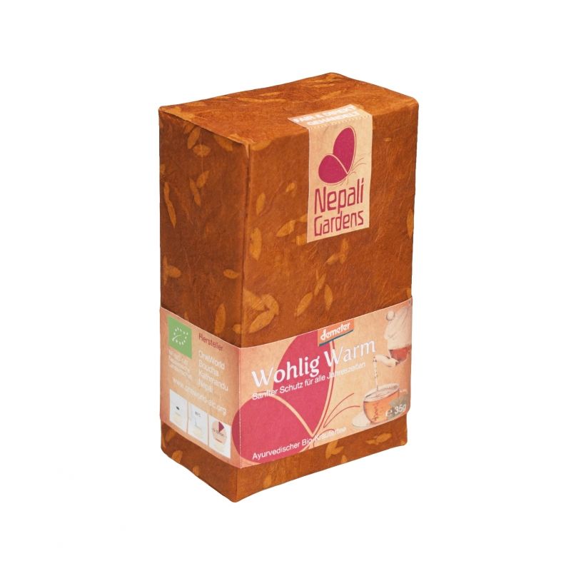 Kartonverpackung mit Aufschrift "Nepali Gardens". Aufkleber mit "Wohlig Warm". Braune Verpackung mit Blättermuster und Logo.