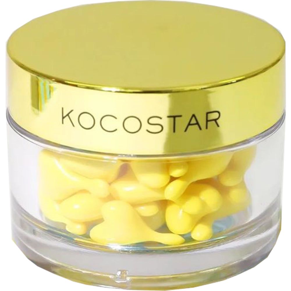 Behälter mit gelben Kapseln. Deckel mit KOCOSTAR-Schriftzug. Klare, zylindrische Basis. Goldfarbener Deckel.