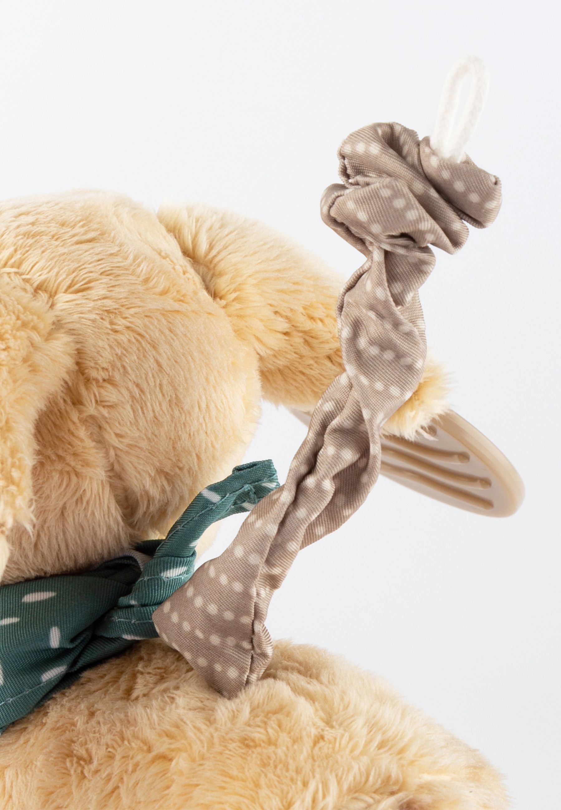 Detailaufnahme des Stoffhundes mit Gummi-Zahnungshilfe und grünem Halstuch. Beige, gepunktete Schleife.