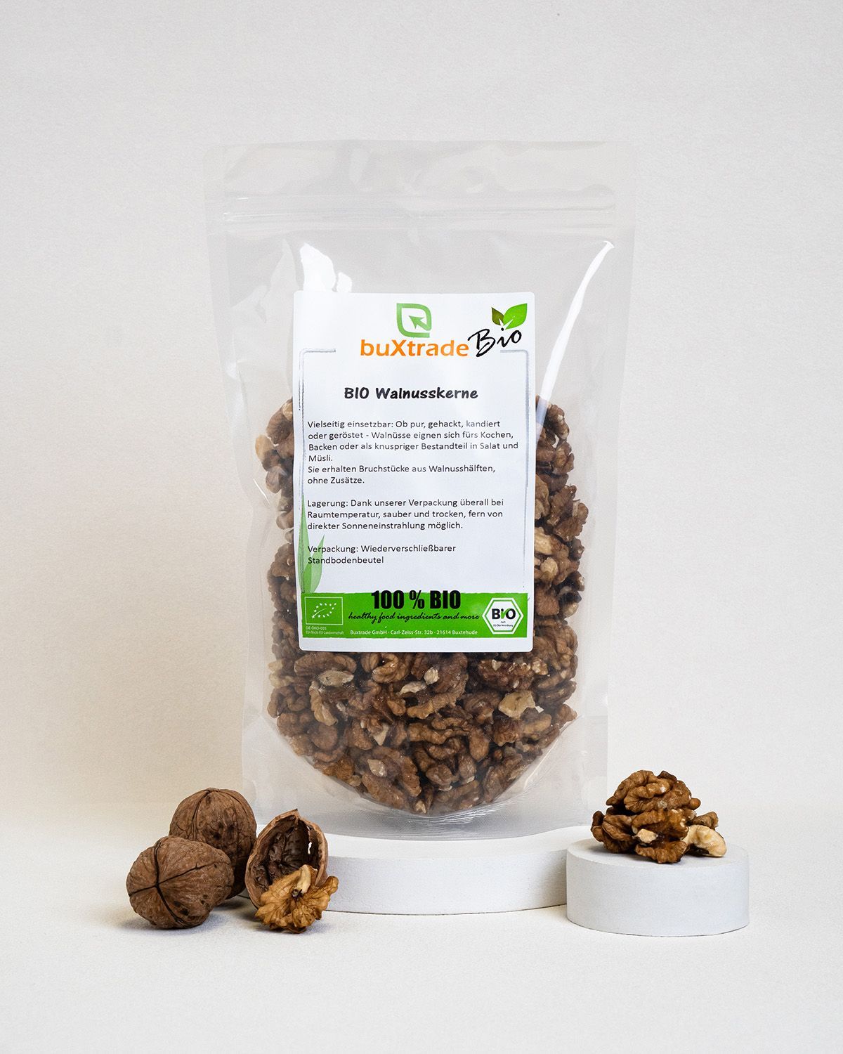Verpackung mit buXtrade Bio Walnusskernen. Walnüsse und Kerne auf Podesten. Bio-Siegel und Produktinformationen.