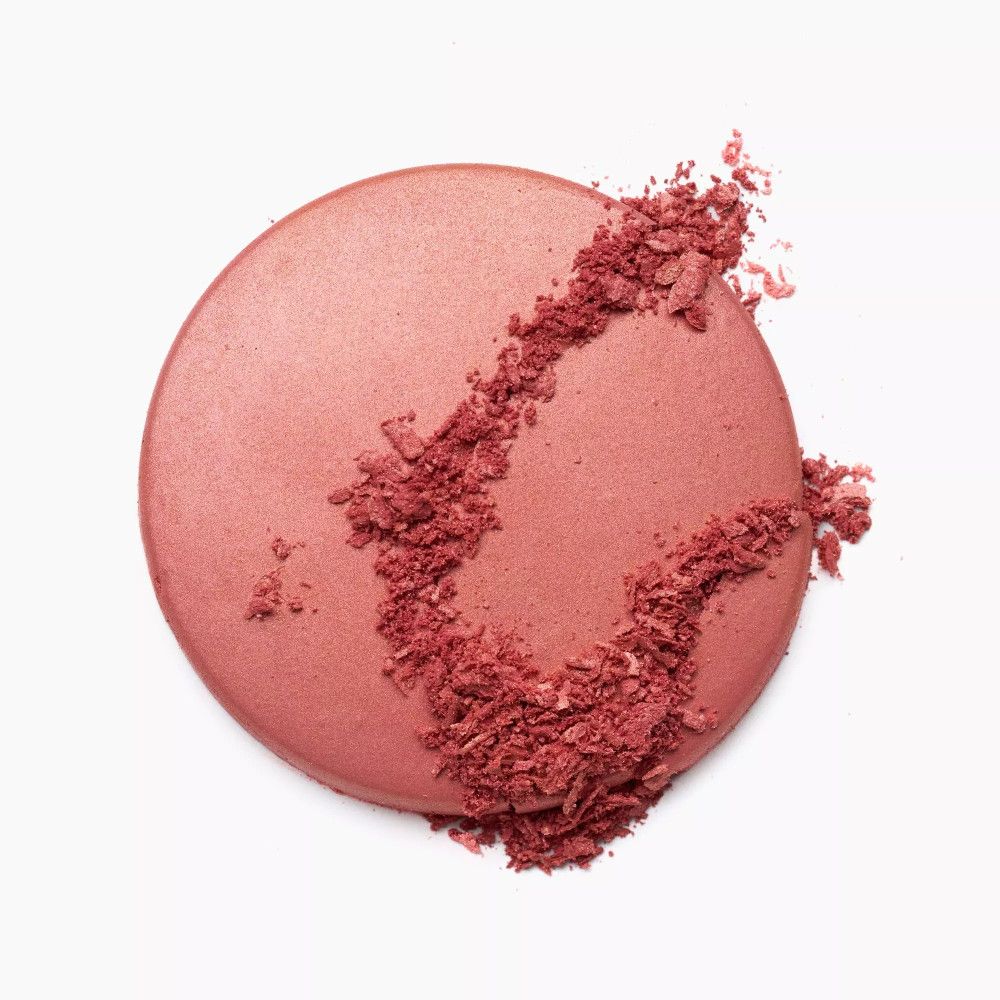 Runder, rosafarbener Rouge-Puder mit zerbröseltem Puder auf weißem Hintergrund.