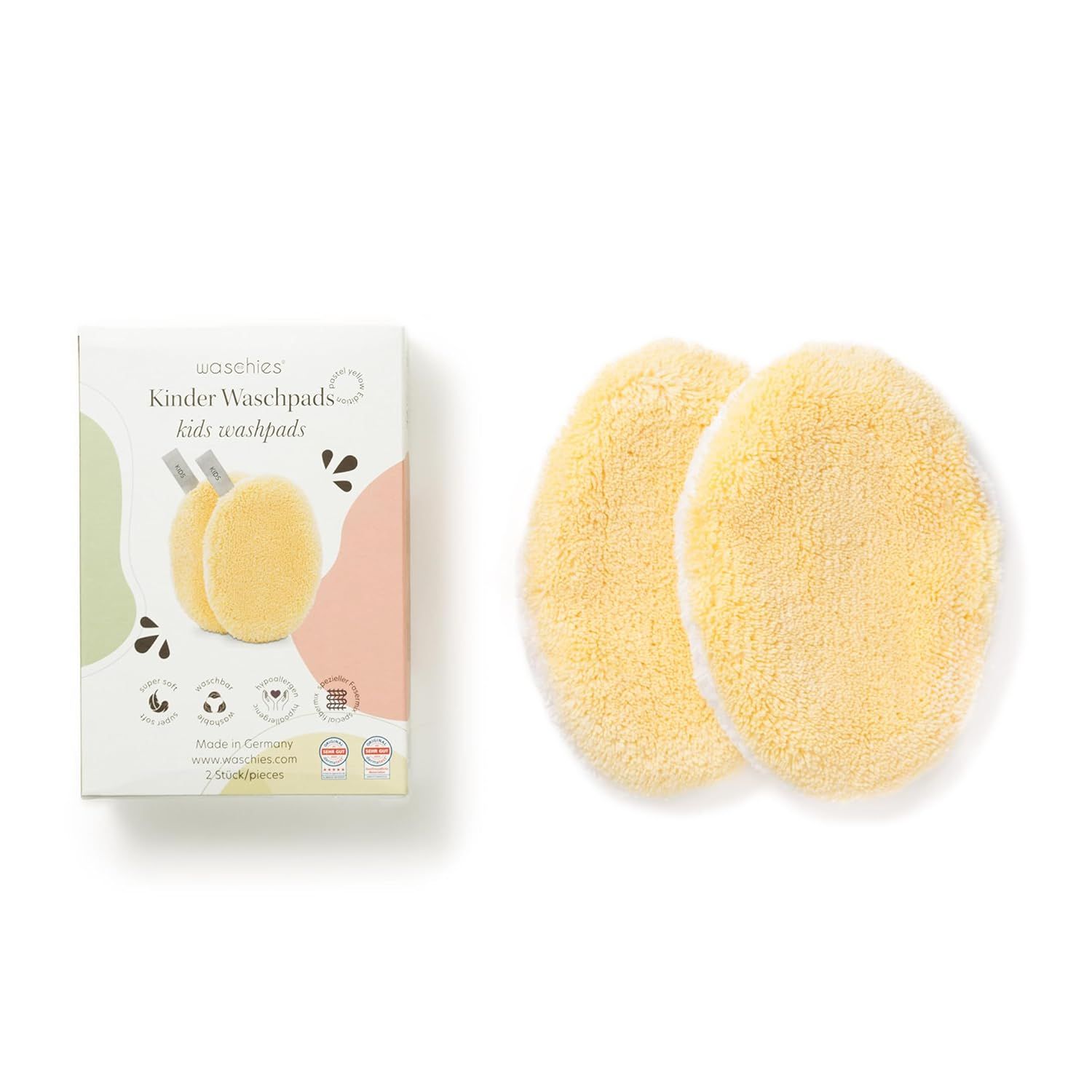 Zwei gelbe Waschpads neben einer Verpackung. Verpackung: Waschies Kinder Waschpads, 2er Set. Logo: Made in Germany, vegan, dermatologisch getestet.