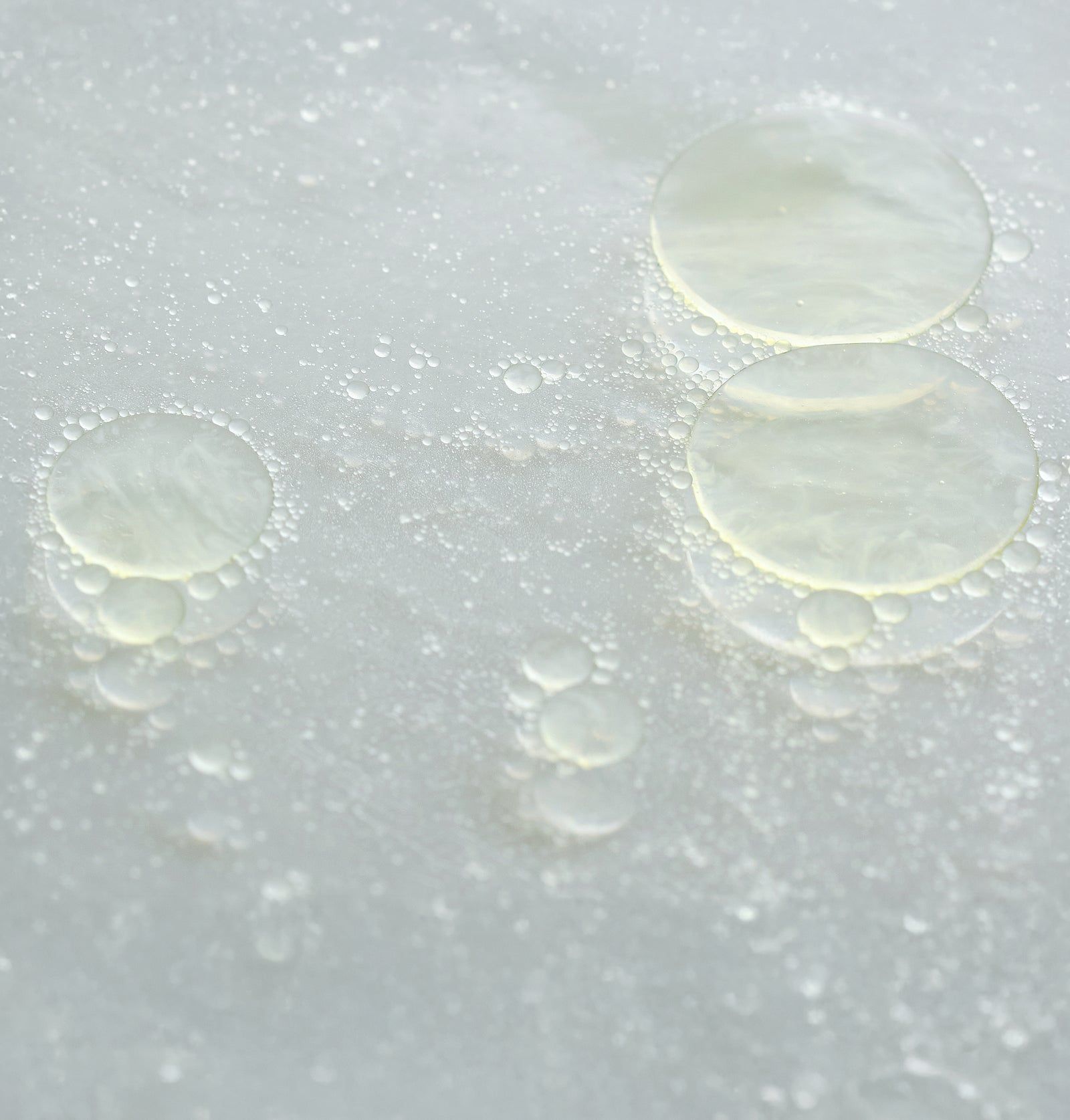 Nahaufnahme von Öltröpfchen auf einer Oberfläche. Runde Formen, transparente Flüssigkeit.