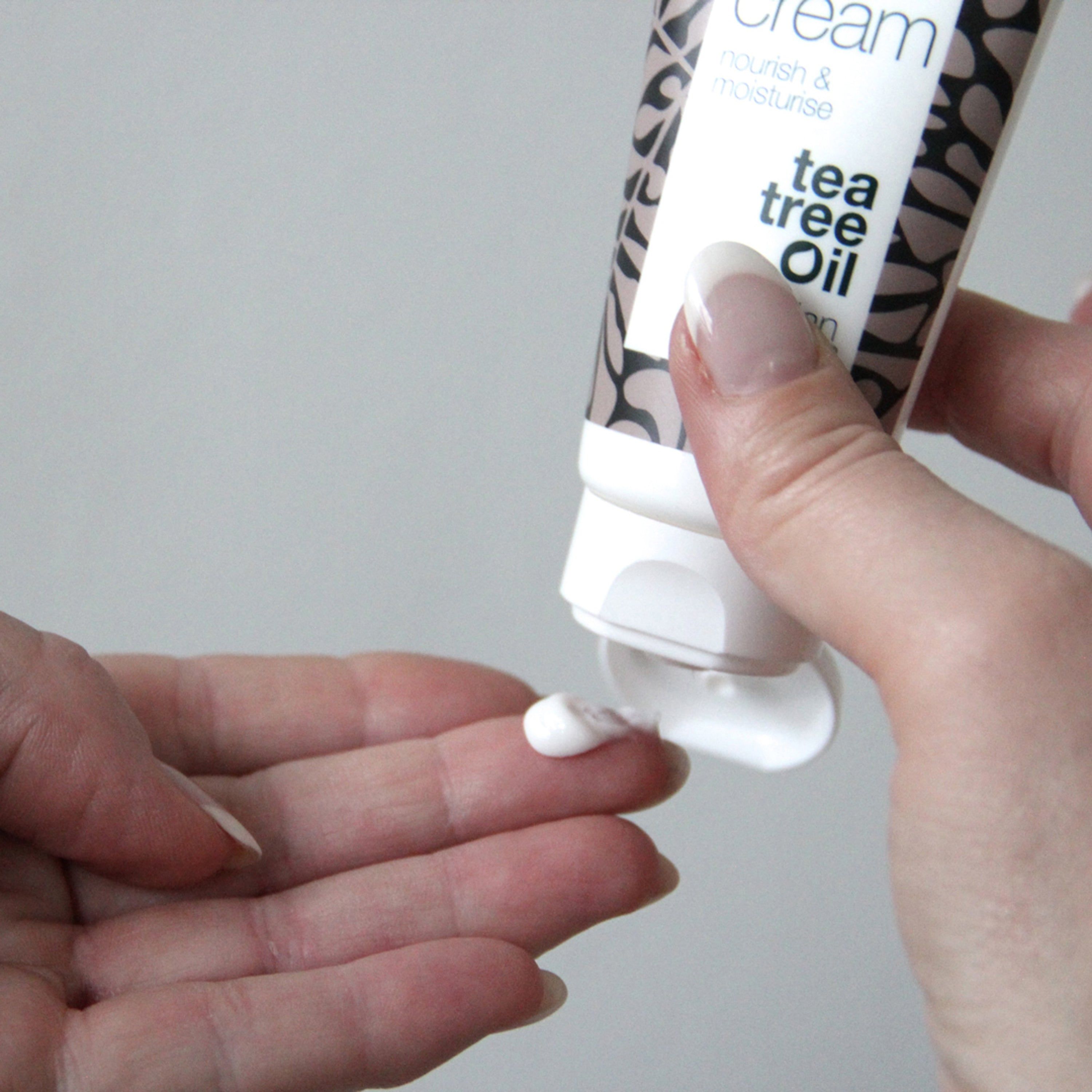 Person drückt Creme aus Tube. Text: face cream, nourish & moisturise, tea tree oil, Australian Bodycare.