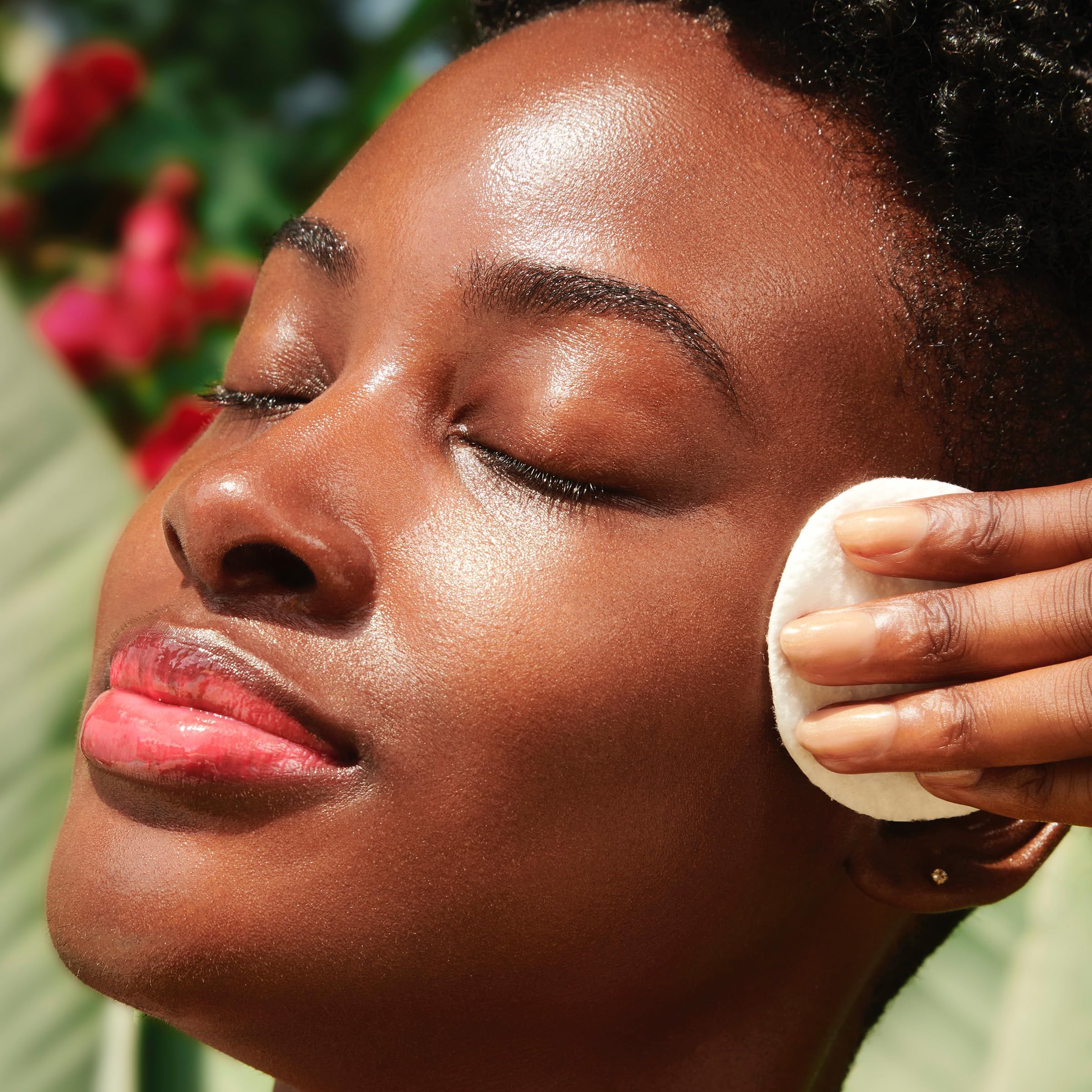 Person wischt mit einem Wattepad über das Gesicht. Augen geschlossen, Haut glänzend.