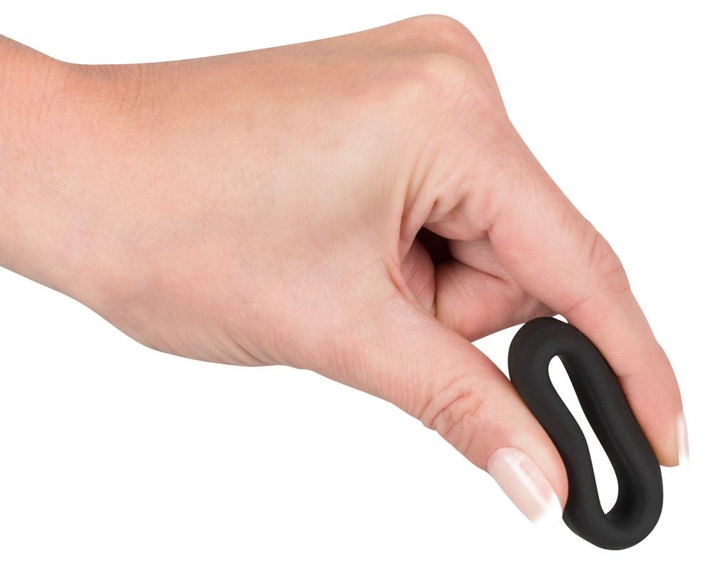 Schwarzer Penisring in einer Hand gehalten. Ring ist länglich verformt.