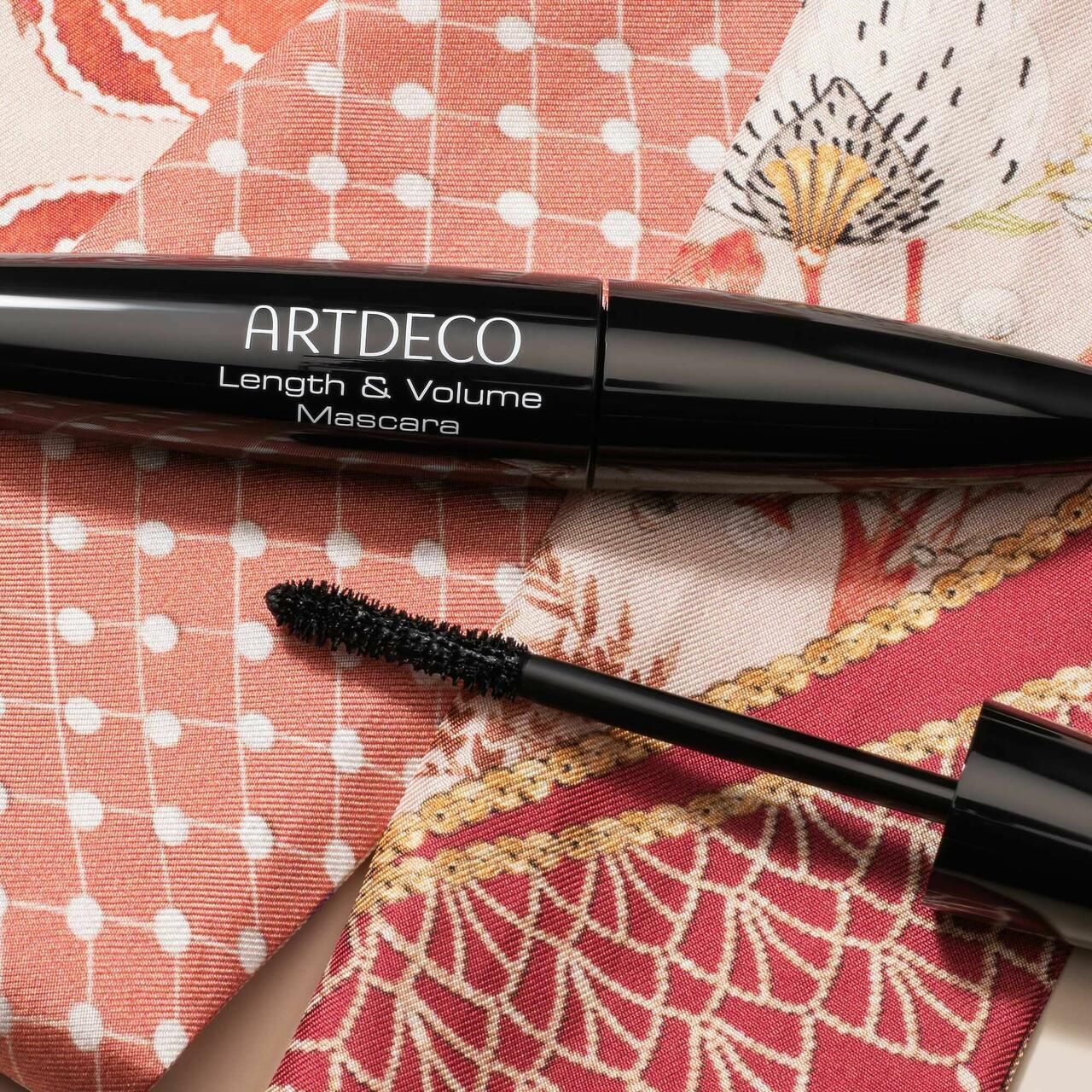 Schwarze Mascara-Tube und Bürste auf Stoff. Auf der Tube steht "ARTDECO Length & Volume Mascara".