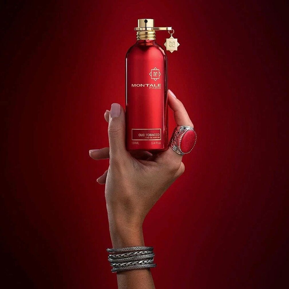 Roter Flakon in einer Hand. Goldfarbener Verschluss und Anhänger. Aufschrift: Oud Tobacco, Eau de Parfum.