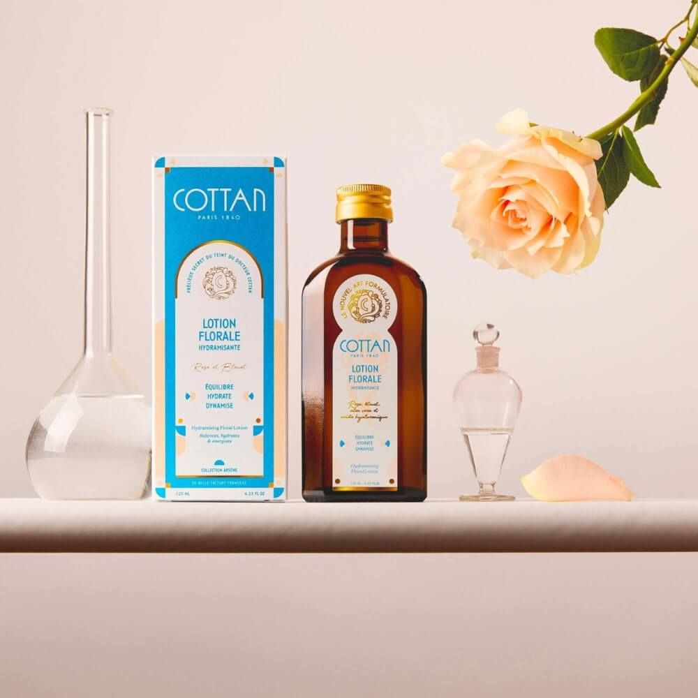 Braune Glasflasche und Schachtel mit "COTTAN"-Logo und "Lotion Florale". Eine Rose und Laborutensilien sind ebenfalls zu sehen.