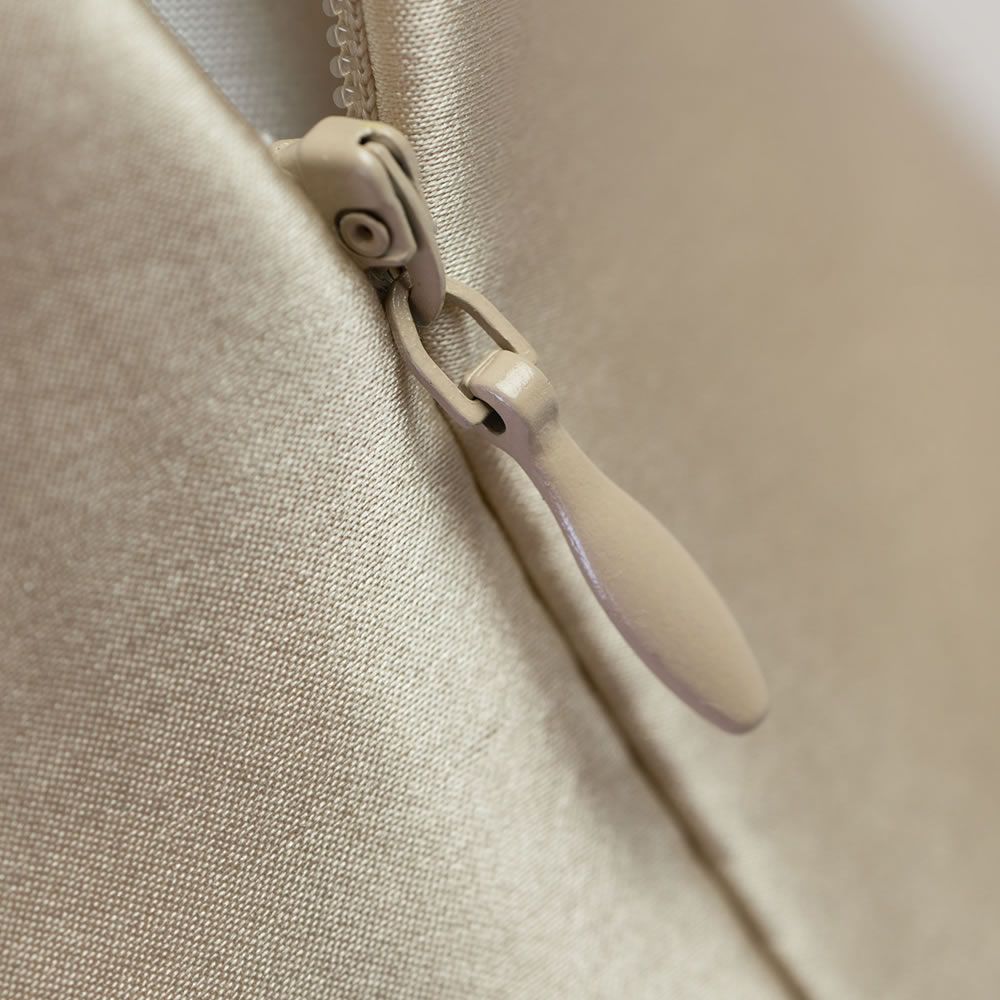 Nahaufnahme eines Reißverschlusses an einem beigen Seidenkissenbezug. Der Reißverschluss ist ebenfalls beige.