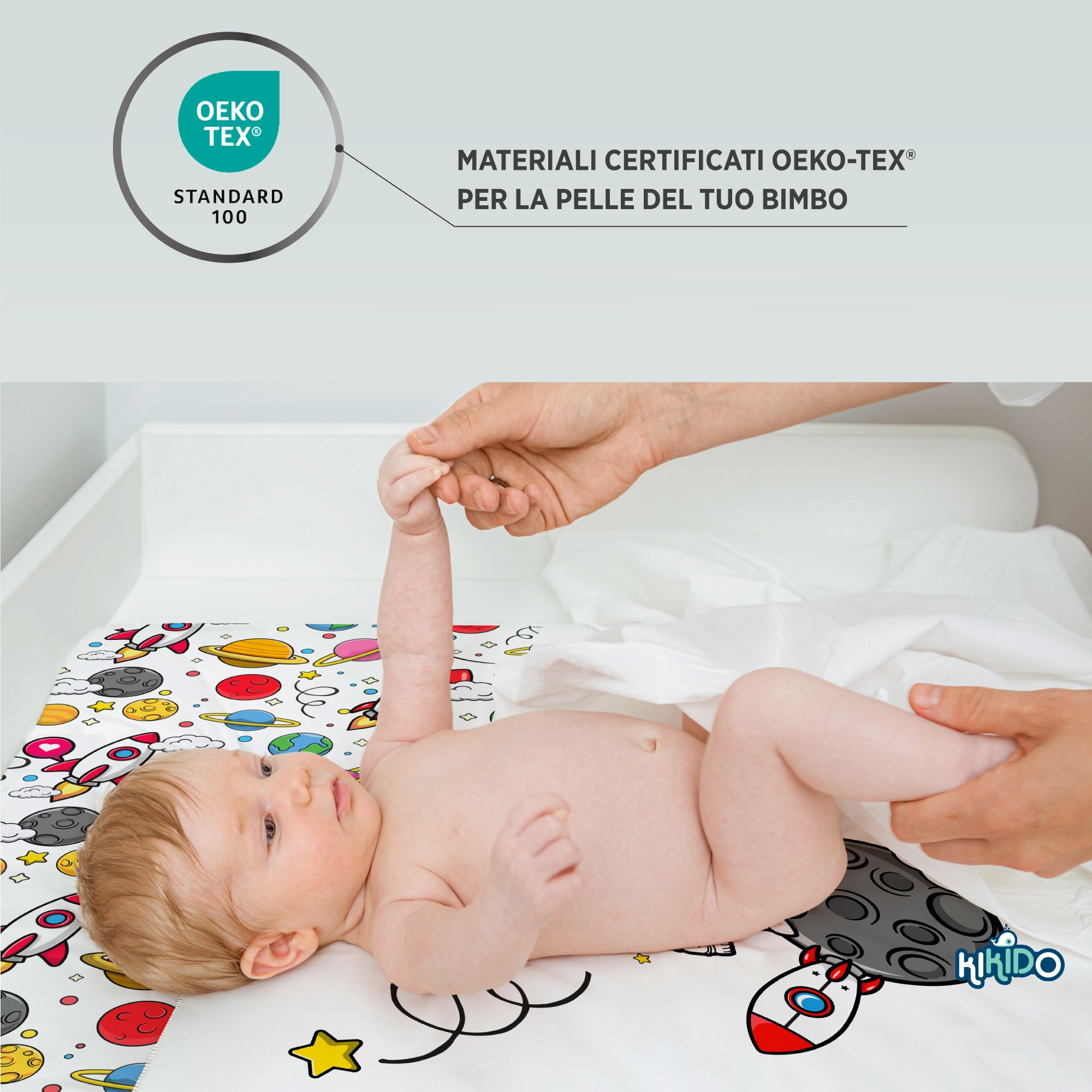 Baby liegt auf Wickelauflage mit Weltraum-Motiv. Oeko-Tex Standard 100 Zertifizierung. Kikido Logo.