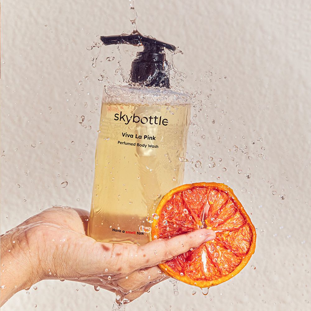 SKYBOTTLE Viva La Pink Duschgel-Flasche mit Wasserstrahlen und Grapefruit-Hälfte. Schwarzer Spender. Text: Viva La Pink, Perfumed Body Wash.