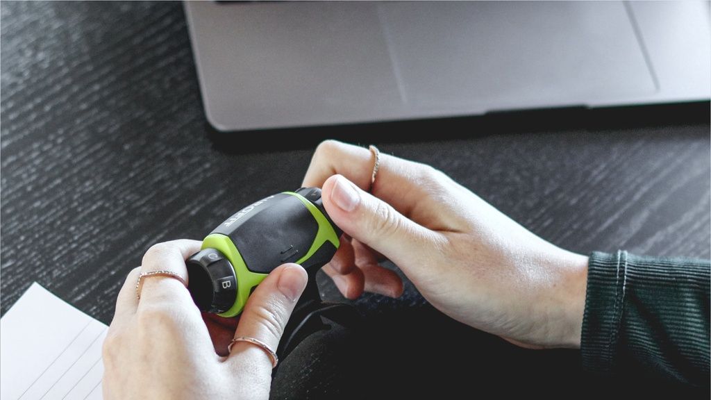 Hände halten einen Atemtrainer. Schwarz-grünes Gerät. Auf dem Gerät sind Zahlen zu sehen.