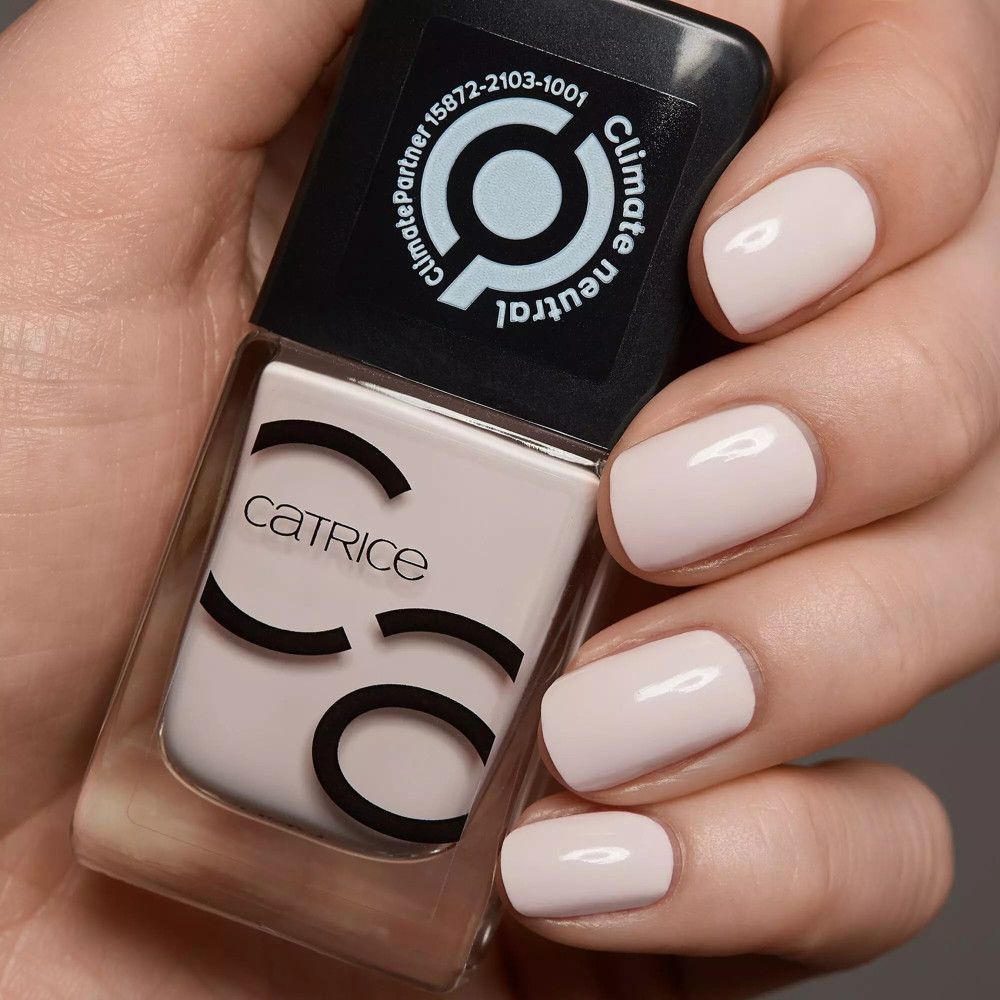 Hand mit lackierten Nägeln und Nagellackflasche. Catrice Iconails Nagellack in hellem Rosa.