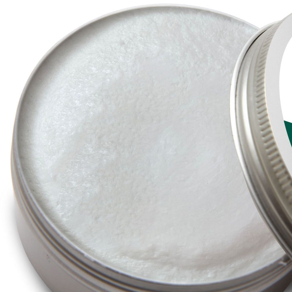 Geöffnete Dose mit Stylingcreme. Cremefarbene Creme in einer runden Dose. Der Deckel liegt daneben.