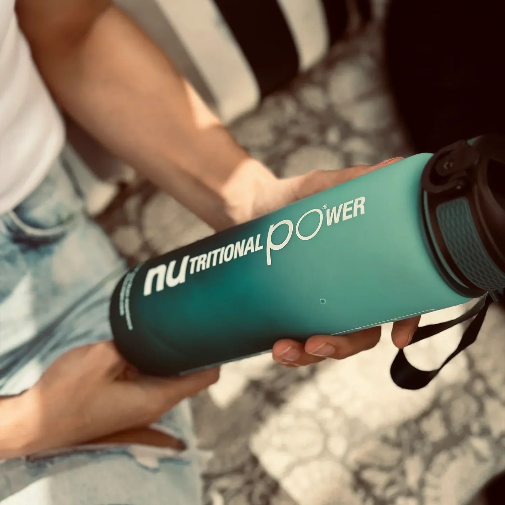 Person hält Wasserflasche. Blau-grüner Farbverlauf. Text: "nu TRITIONAL POWER".