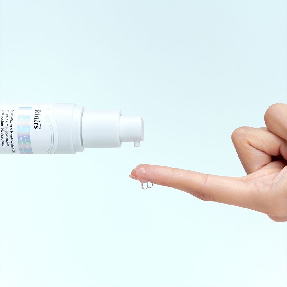Weißes Serum-Fläschchen, Tropfen Serum auf Finger. Aufschrift: klairs. Hintergrund: hellblau.