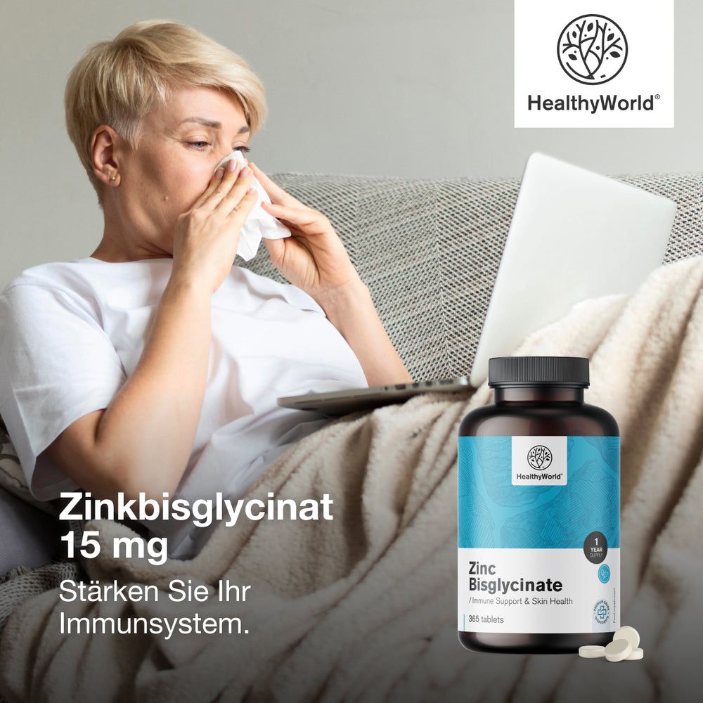 Frau mit Taschentuch, Laptop und Flasche Zinkbisglycinat. Aufschrift: HealthyWorld, 15 mg. Text: Stärken Sie Ihr Immunsystem.