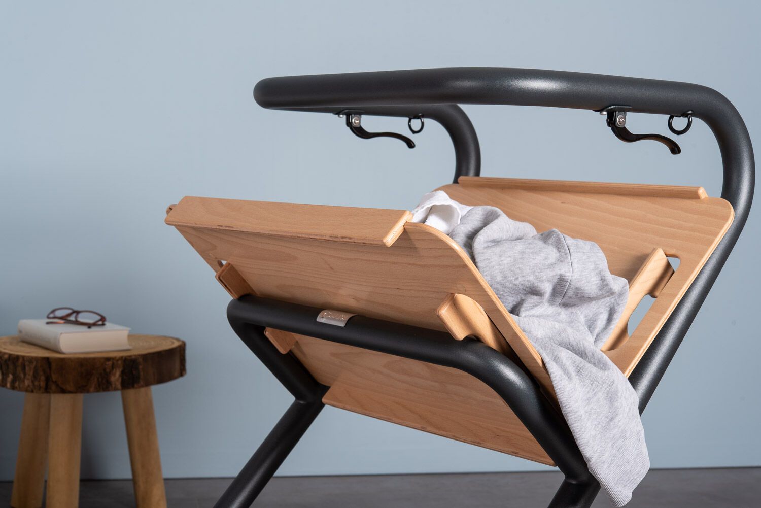 Rollator-Tablett. Holztablett, schwarzer Rahmen. Kleidung auf dem Tablett. Kleiner Holzhocker.