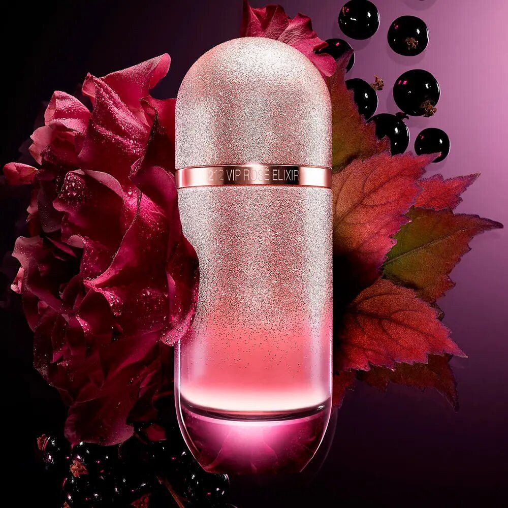Rosafarbener Flakon mit Glitzer. Aufschrift: VIP Rosé Elixir. Umgeben von roten Blättern und schwarzen Johannisbeeren.