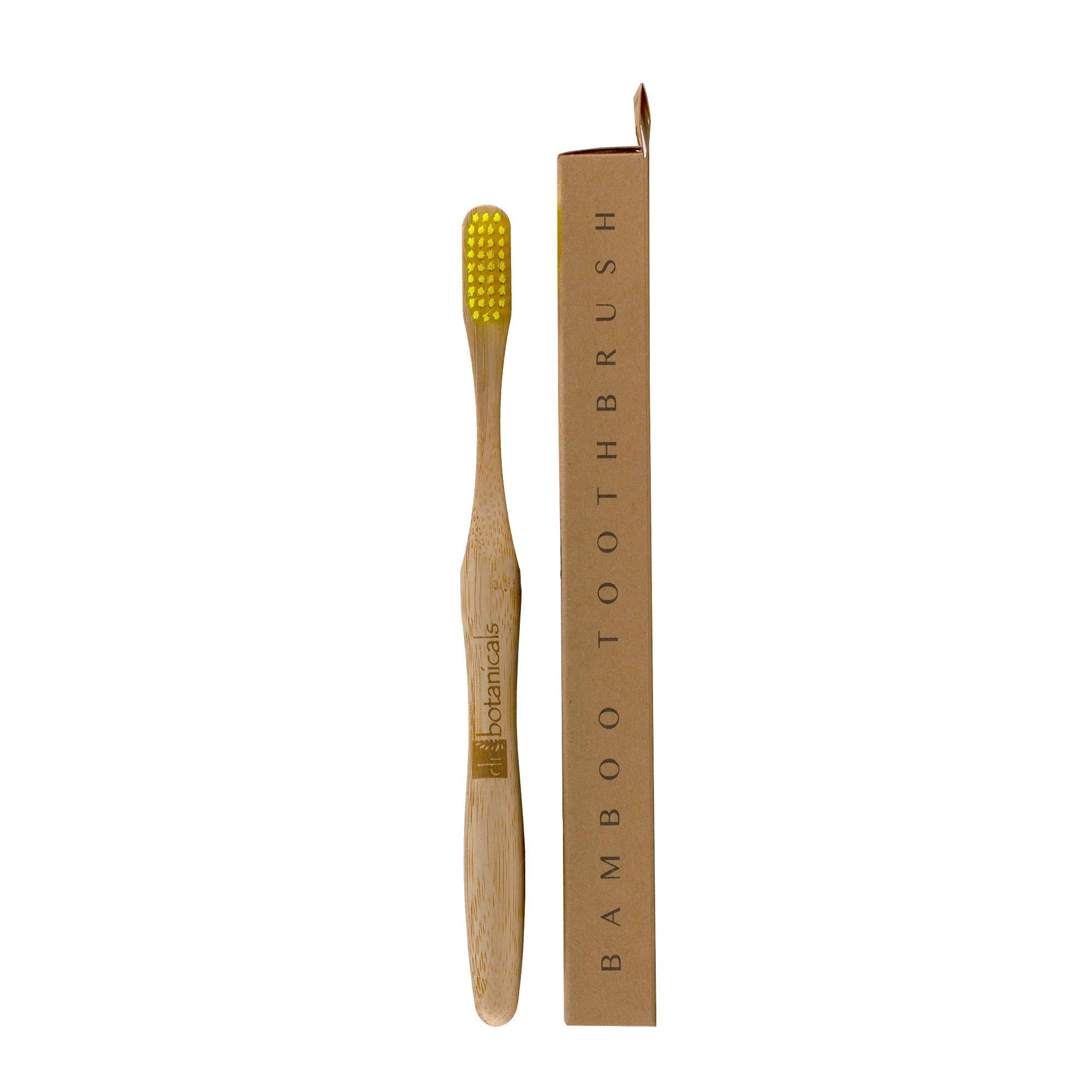 Gelbe Bambus-Zahnbürste mit Verpackung. Aufschrift: Bamboo Toothbrush. Marke: Dr Botanicals.