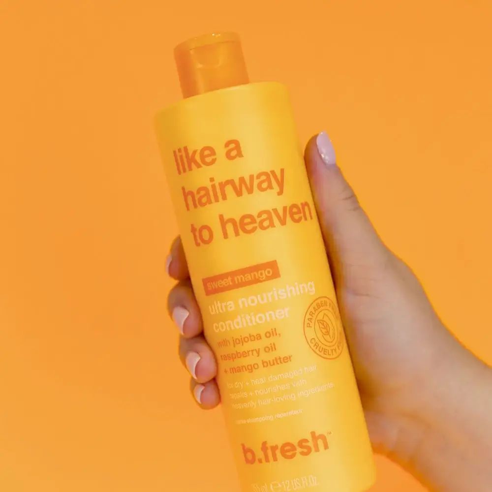 Gelbe Flasche mit Produktnamen und Text. Hand hält die Flasche vor orangefarbenem Hintergrund. B.fresh Logo.