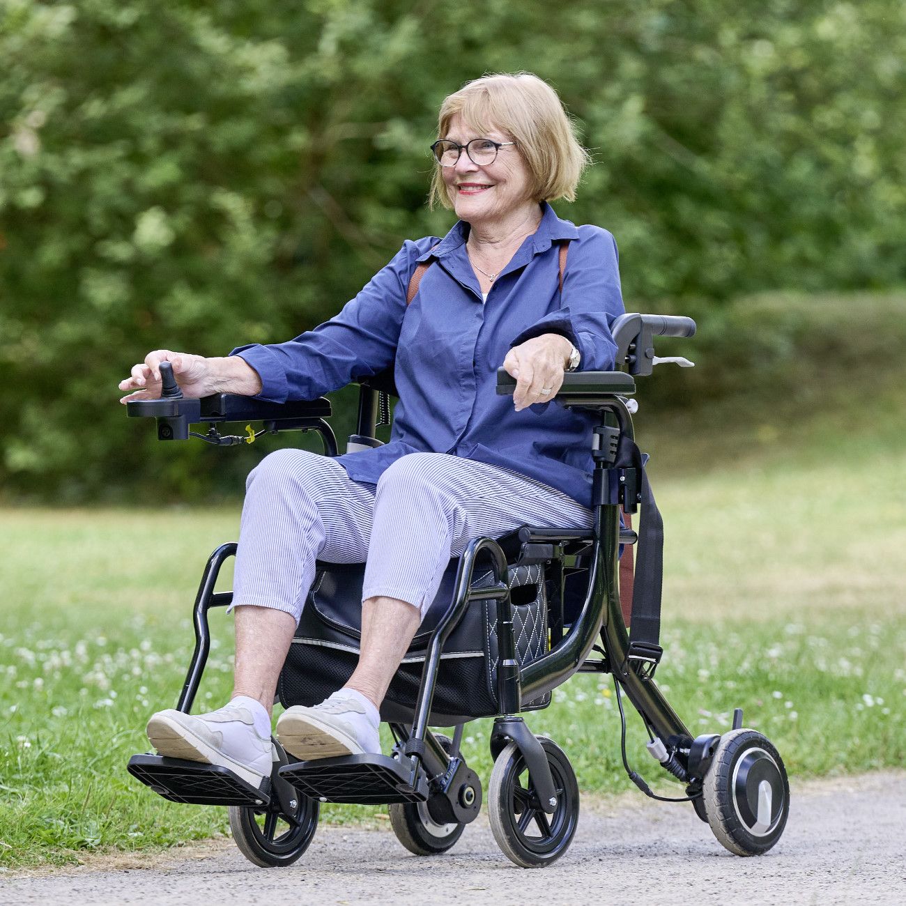 Frau sitzt in einem elektrischen Rollator im Freien.