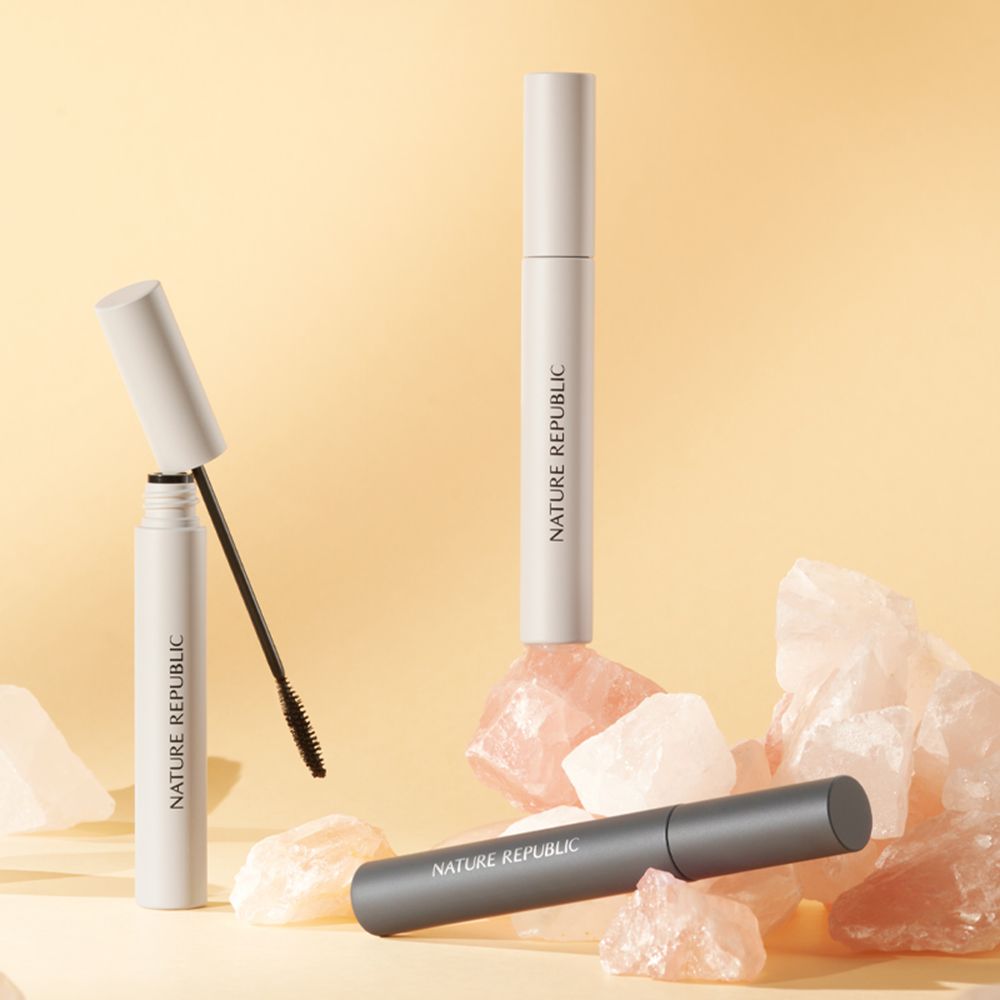 Drei Mascaratuben auf rosa Steinen. Zwei Tuben sind weiß, eine ist grau. Aufschrift NATURE REPUBLIC.