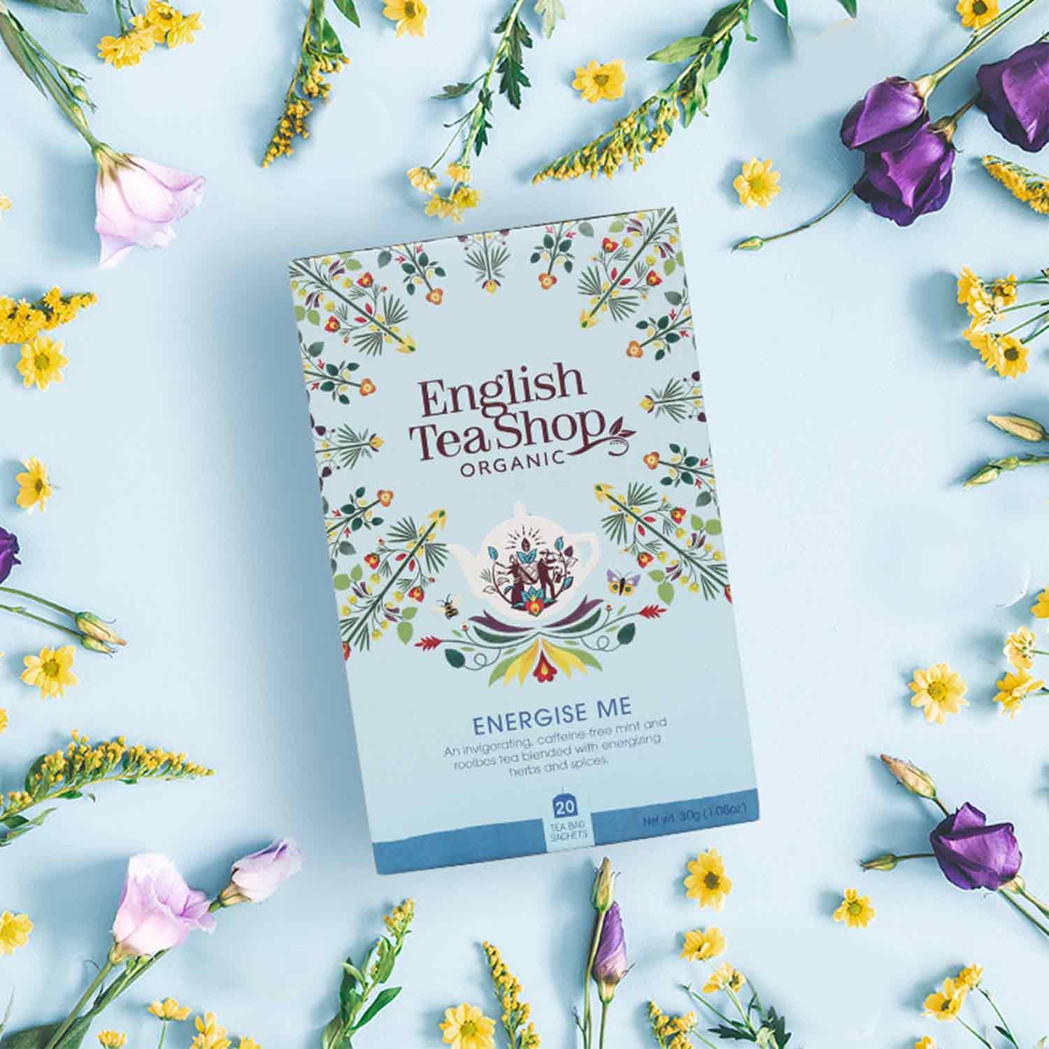 Theepackung mit Aufdruck English Tea Shop ORGANIC, ENERGISE ME, BIO, umgeben von Blumen.