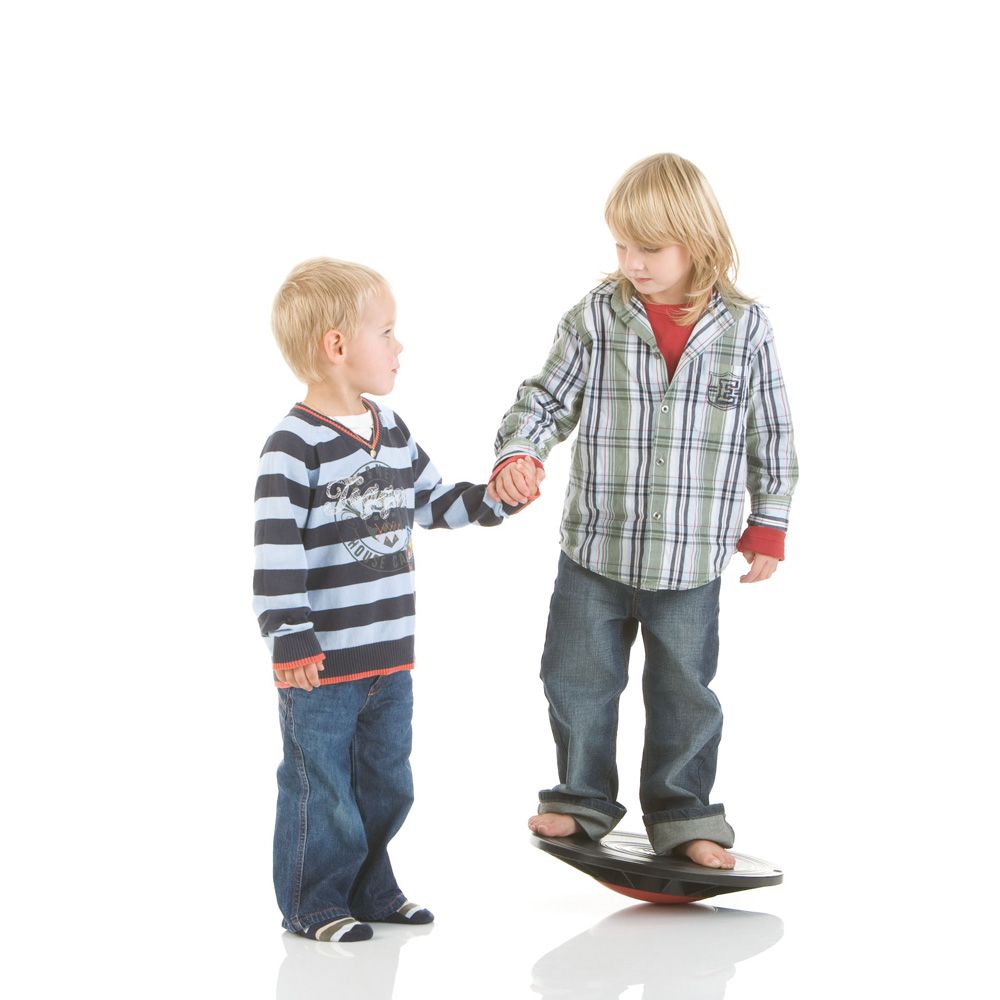 Zwei Kinder auf einem Balance Board. Ein Kind steht darauf, das andere hält die Hand.