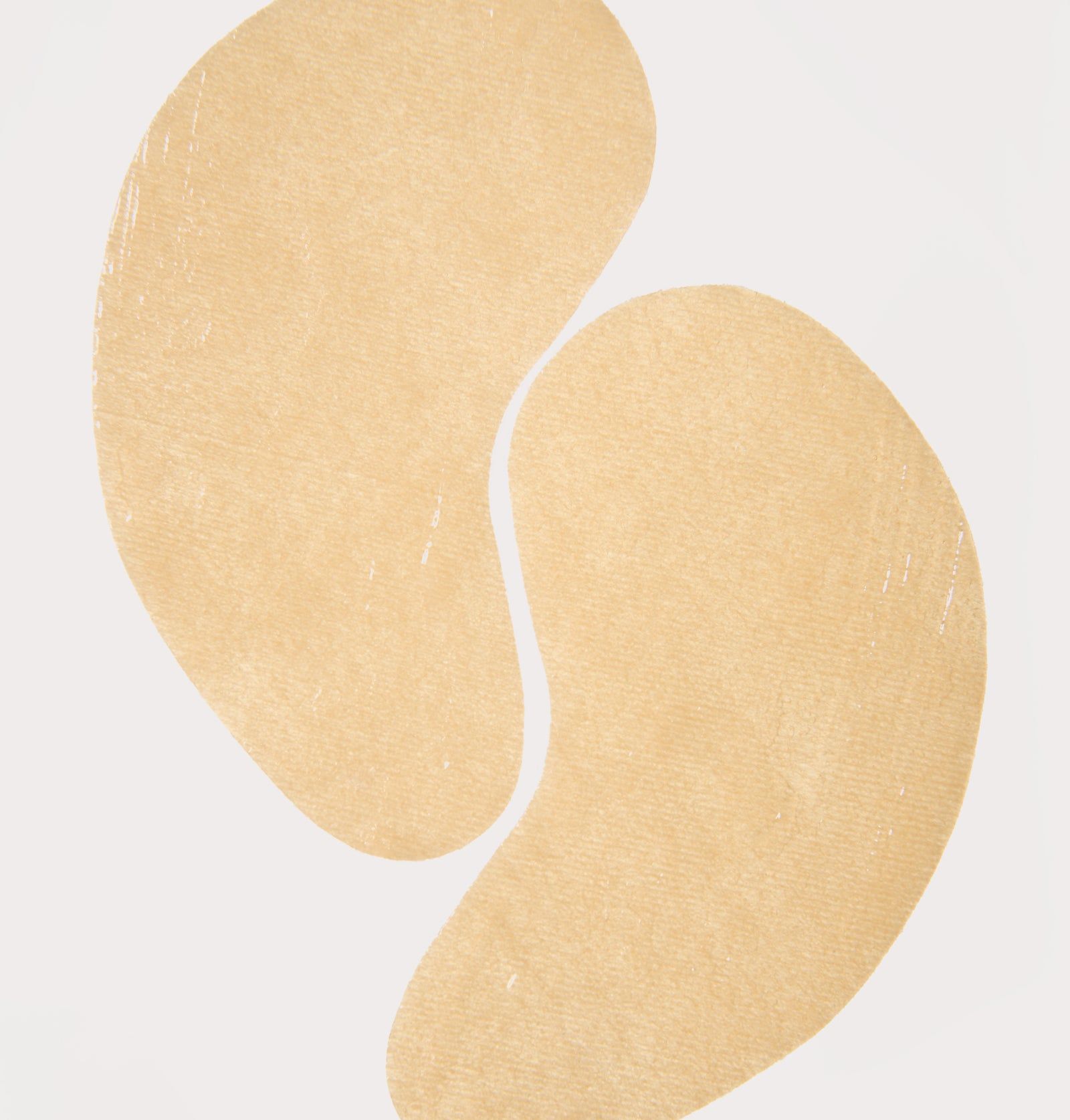 Zwei beige Augenpads. Tropfenförmig. Auf weißem Hintergrund.