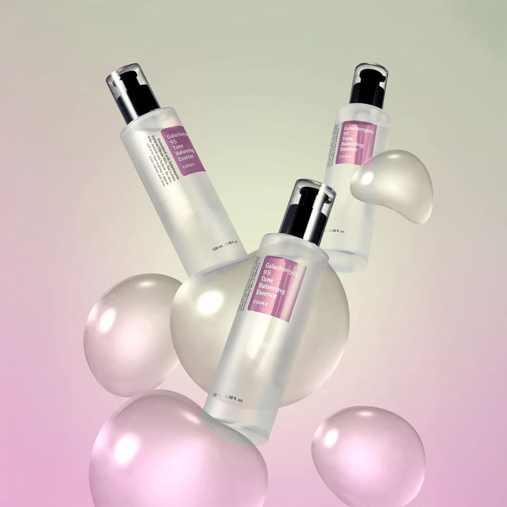 Drei Flaschen Galactomyces 95 Tone Balancing Essence schweben zwischen schwebenden Kugeln.