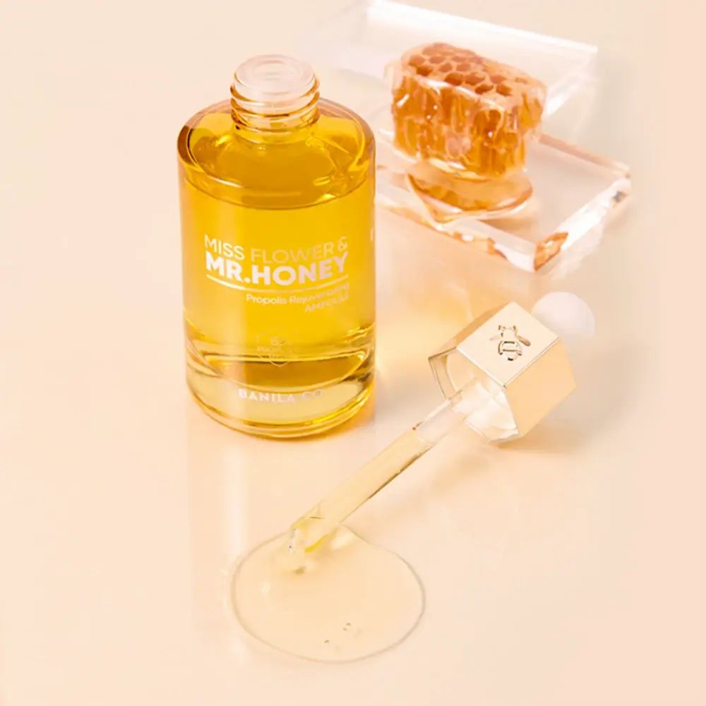 Goldgelbes Serum in Glasflasche mit Pipette und Bienenwaben-Dekoration.