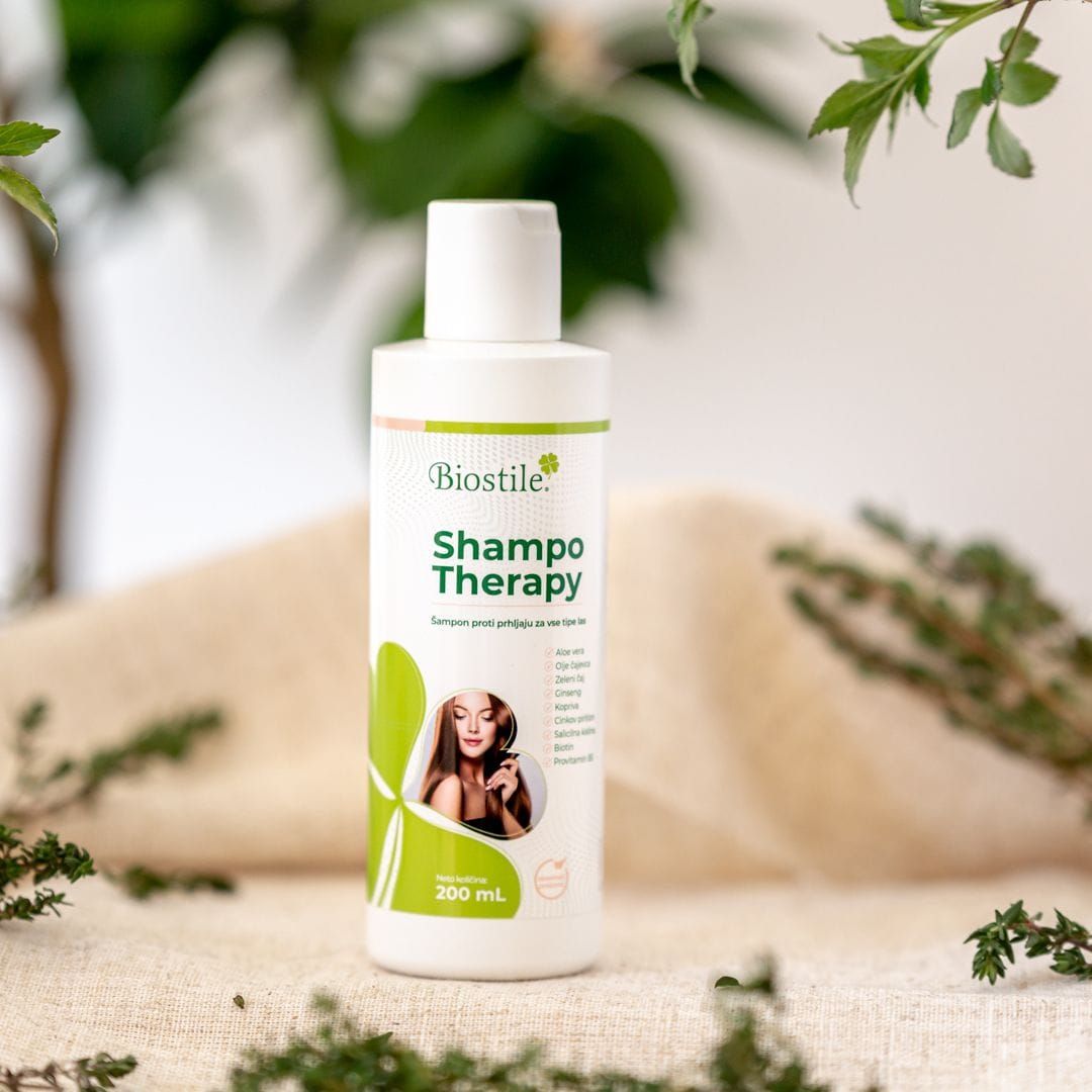 Biostile Shampoo-Therapie Flasche. Weiß, grünes Etikett. Auf Tisch, umgeben von Pflanzen.