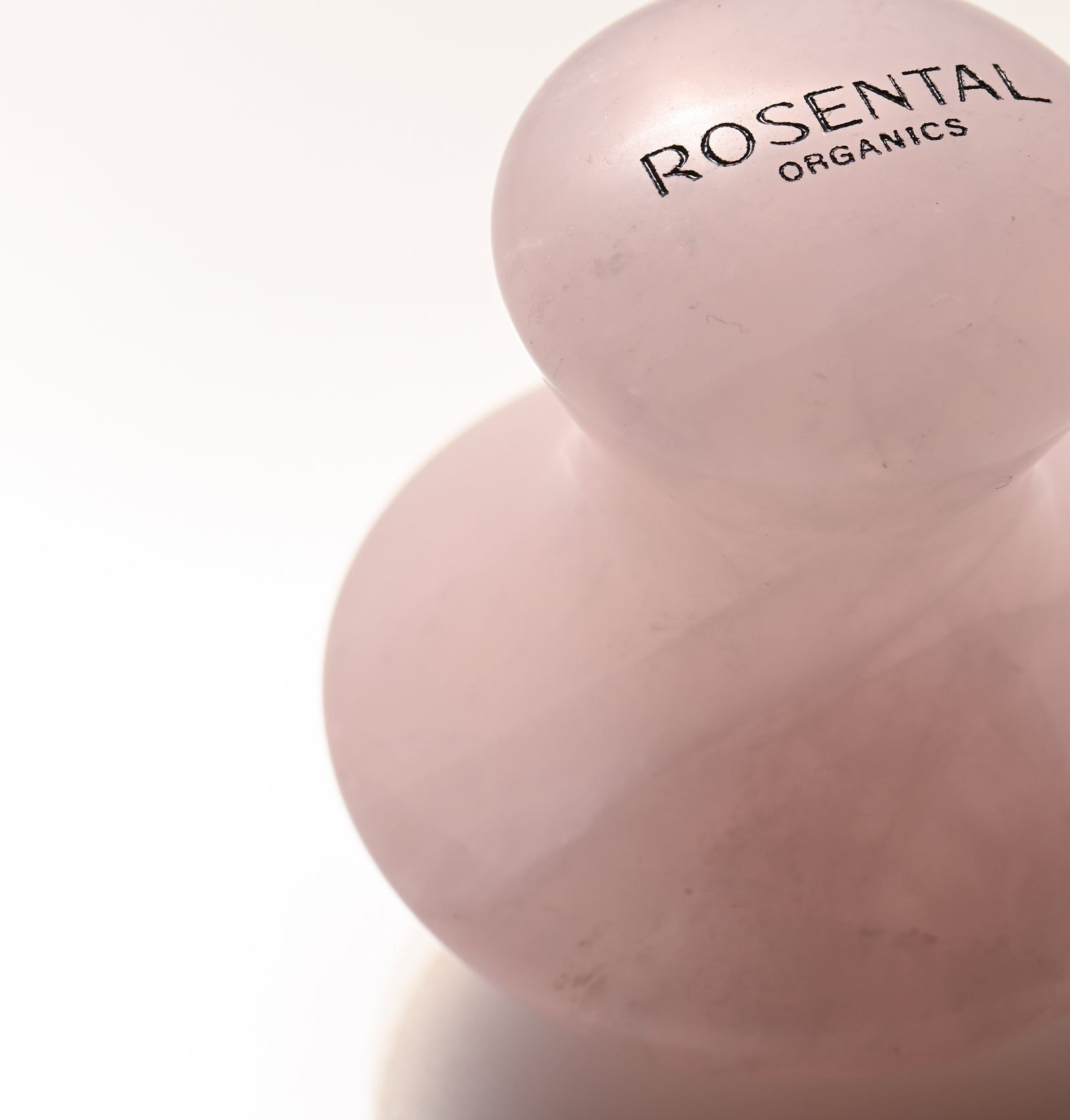 Nahaufnahme eines Eye Flowies Rose Quartz. Der Markenname ist auf dem Stein zu sehen. Der Stein ist rosa und glänzend.