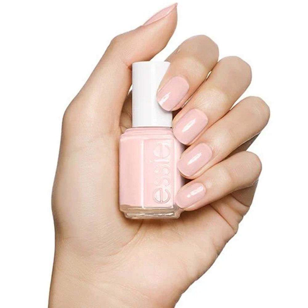 Hand hält Essie Nagellackflasche in zartrosa.