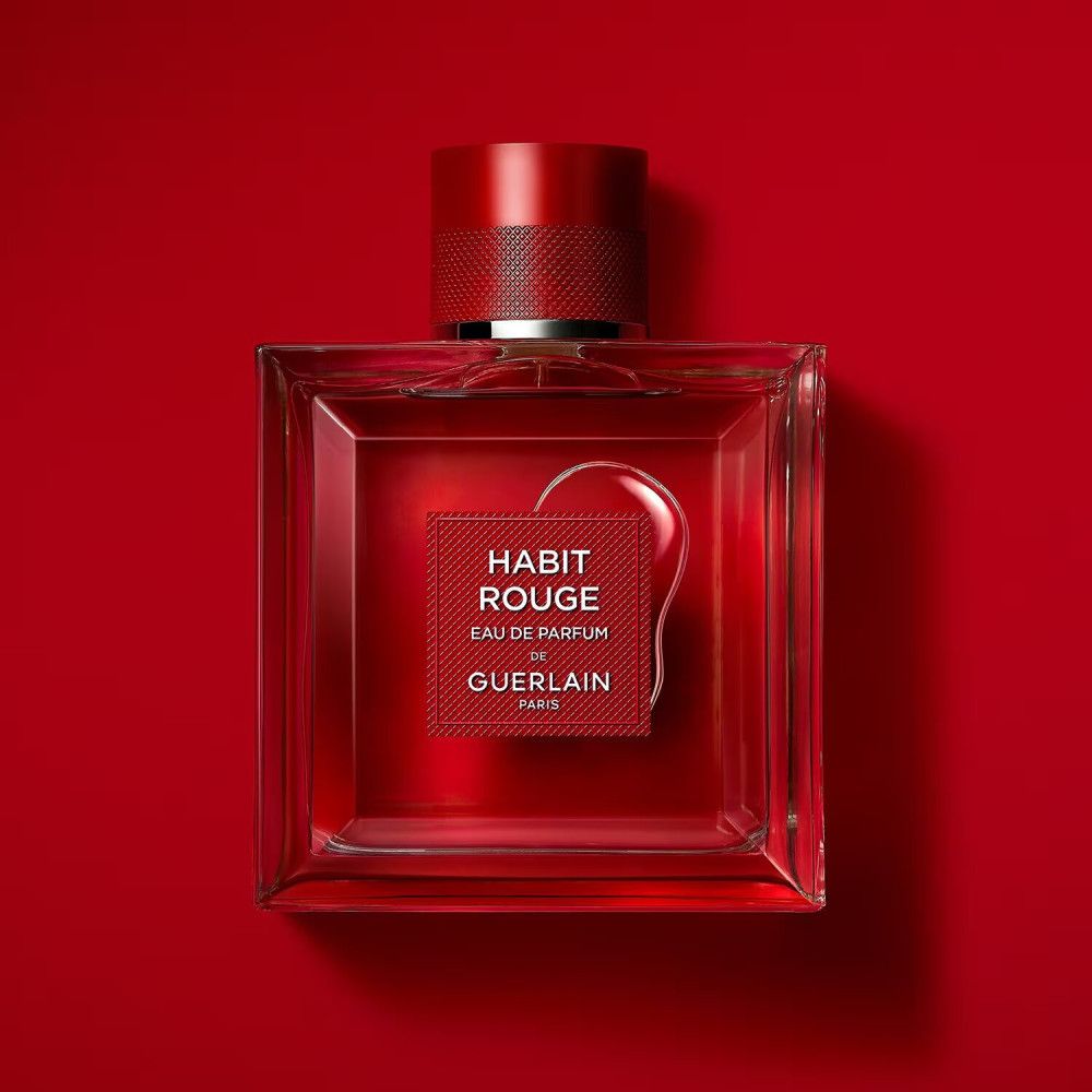 Quadratischer Flakon mit rotem Verschluss und Etikett. Aufschrift: Habit Rouge Eau de Parfum von Guerlain Paris. Roter Hintergrund.