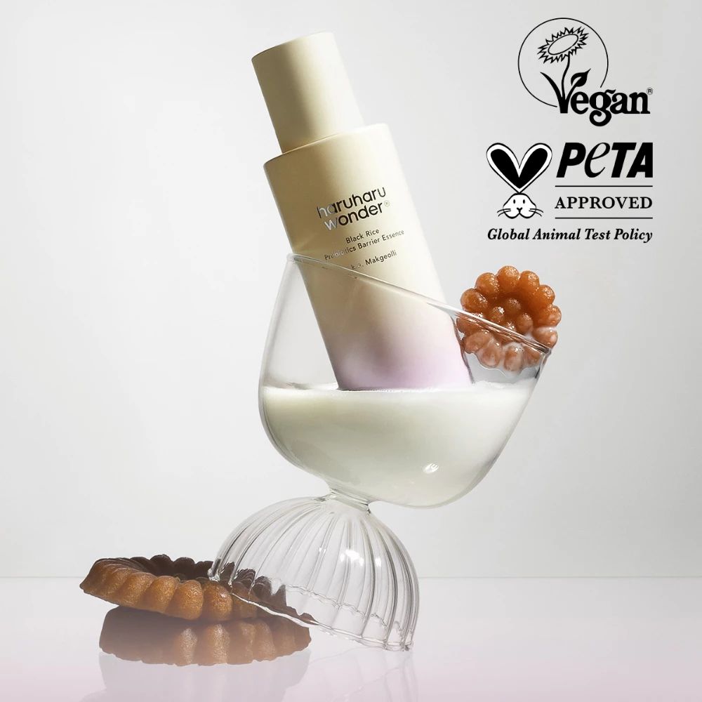 Eine Flasche Haruharu Wonder Black Rice Hyaluronic Barrier Essence in einem Glas mit weißer Flüssigkeit. Vegan und PETA-zertifiziert.