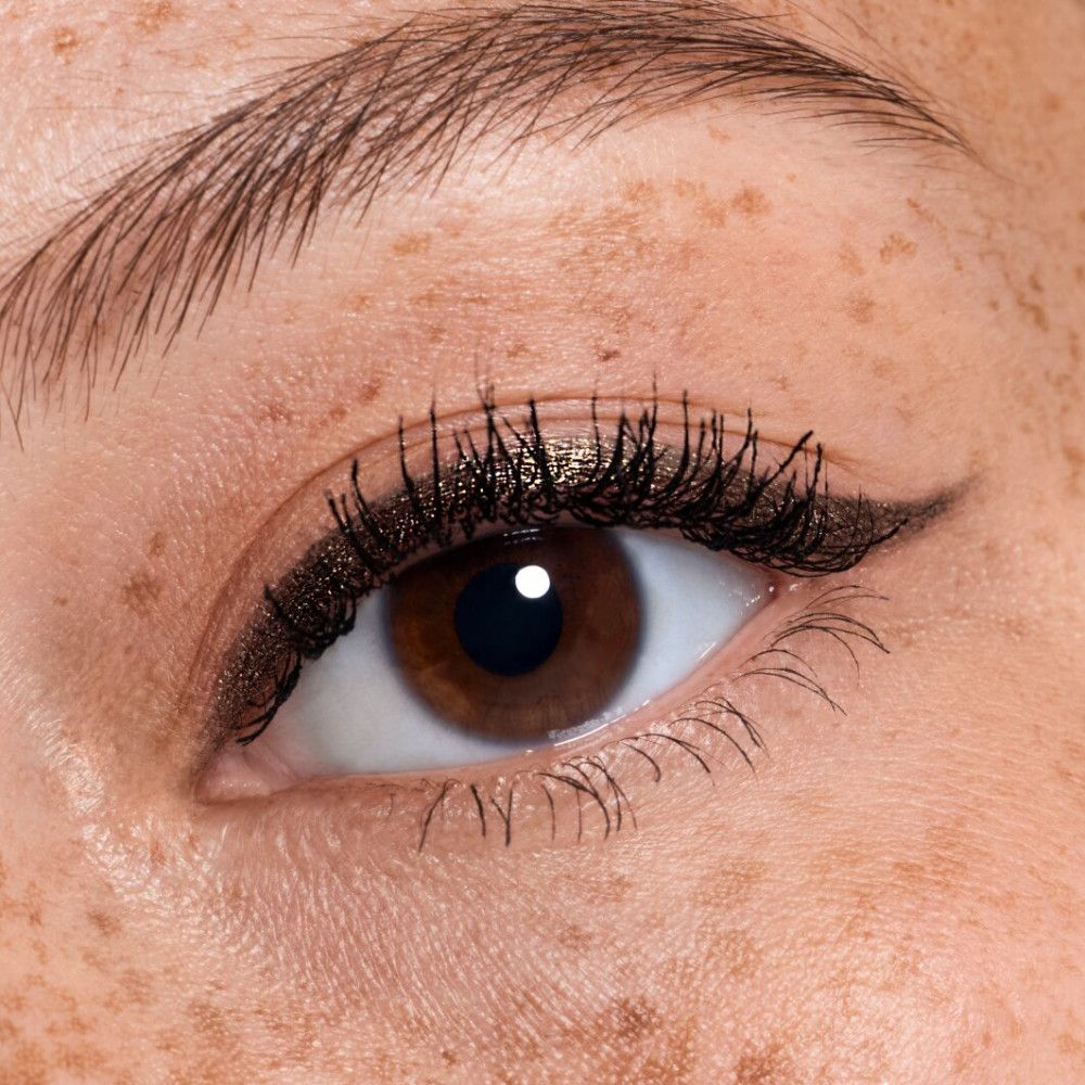 Nahaufnahme eines Auges mit Lidstrich und Wimperntusche. Sommersprossen.