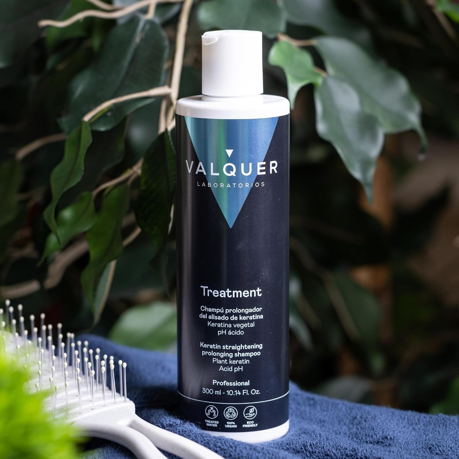 Eine schwarze Flasche Valquer Treatment Shampoo steht auf einer Marmorplatte in einem Badezimmer.