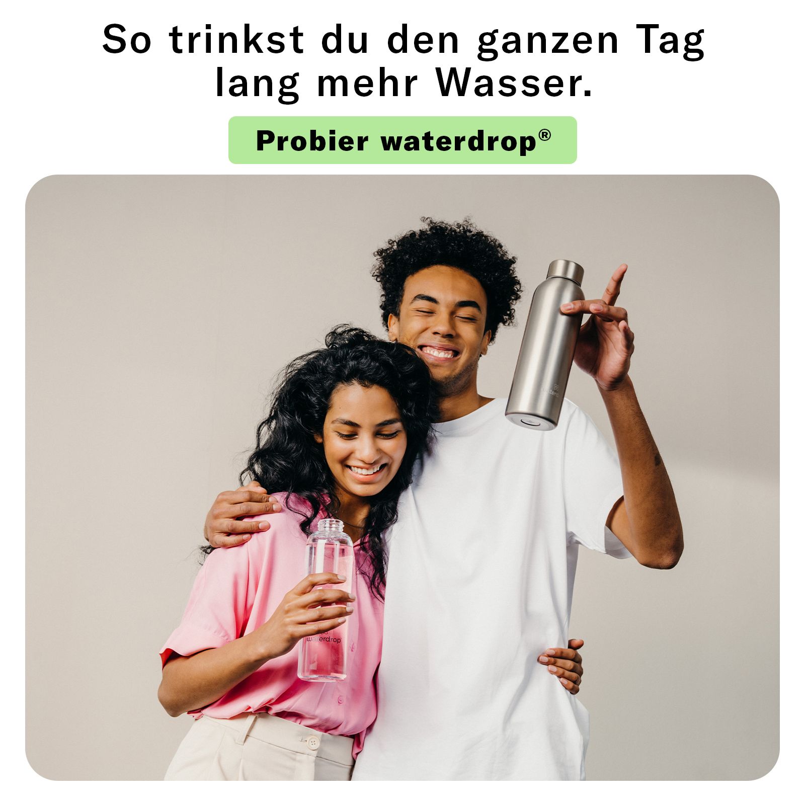 Paar umarmt sich, hält Trinkflaschen. Eine transparente und eine silberne Edelstahlflasche.
