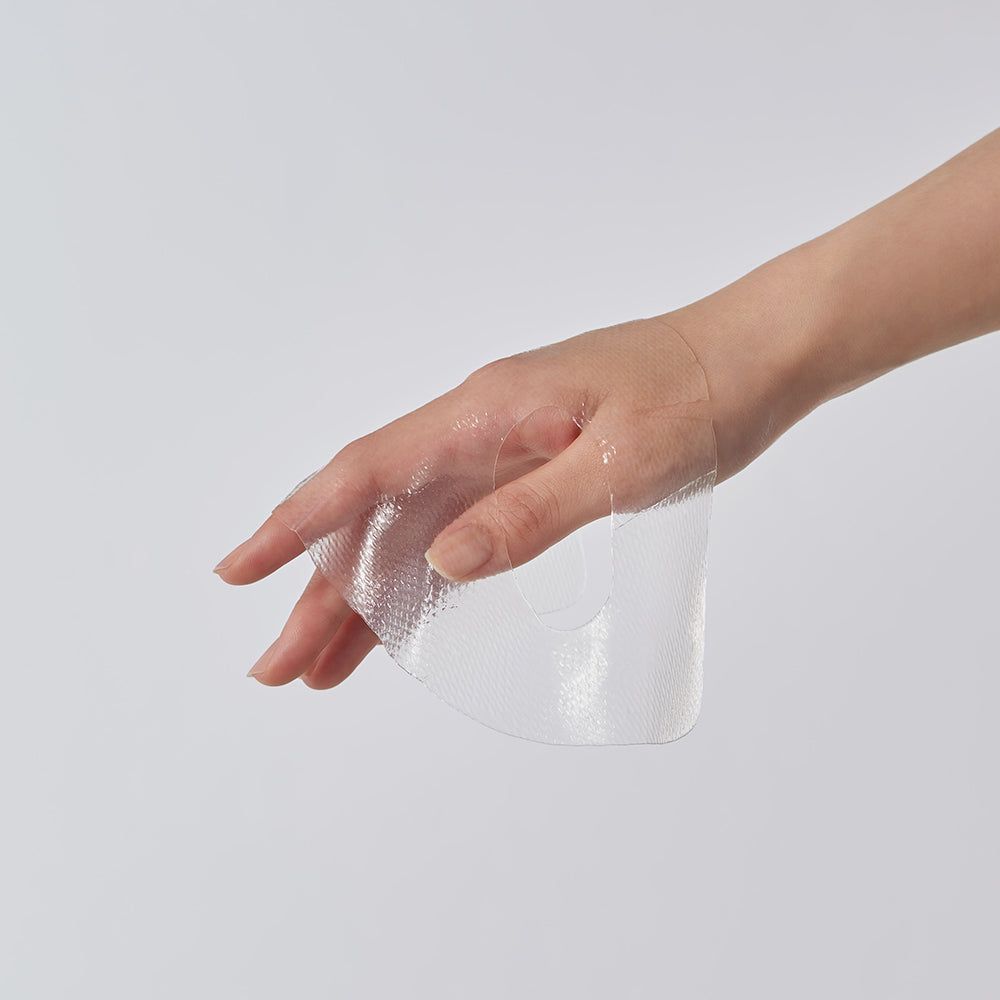Hand hält eine transparente Gesichtsmaske. Die Maske ist feucht und glänzend.