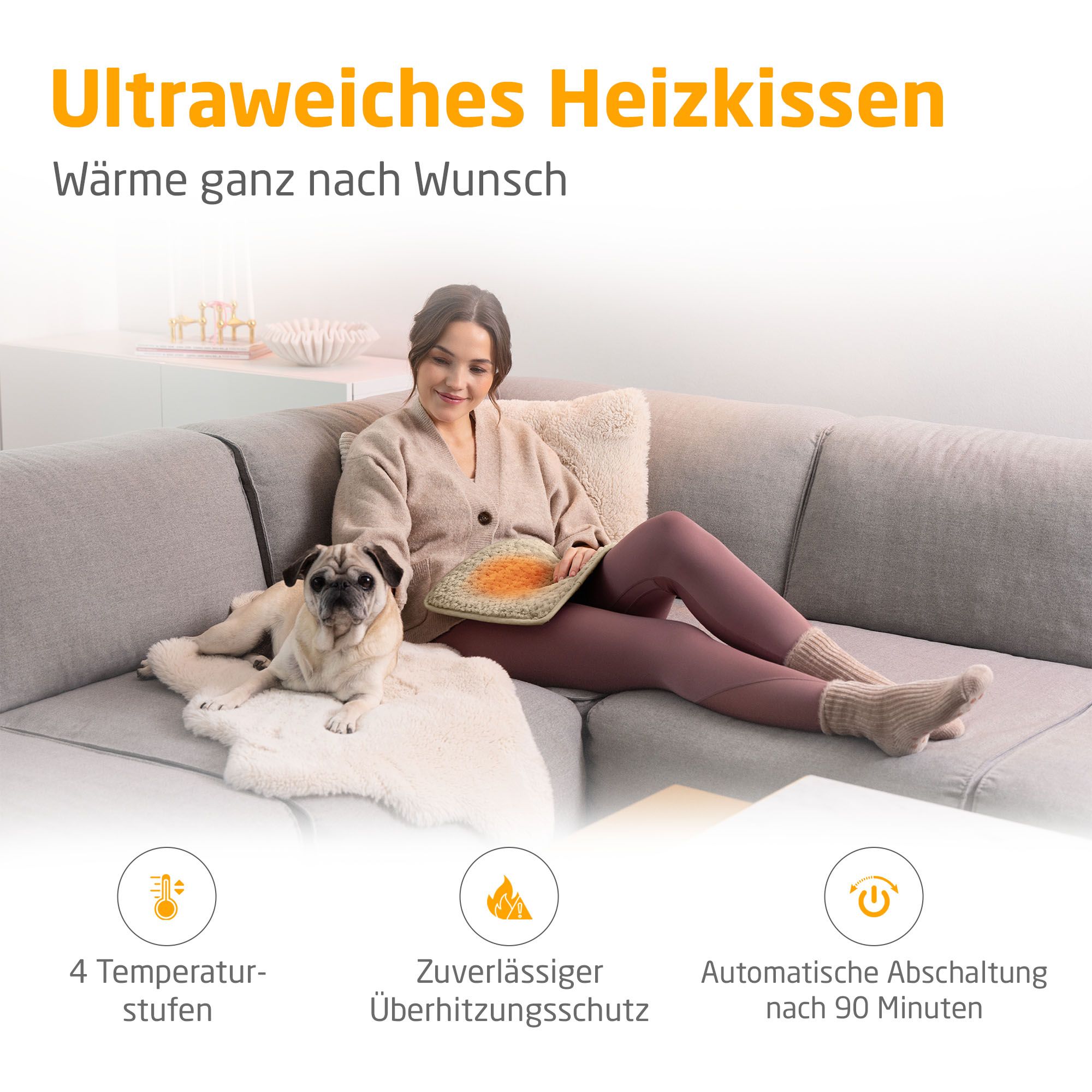 Heizkissen, beige. Frau sitzt auf Couch mit Hund. 4 Temperaturstufen, Überhitzungsschutz, Abschaltautomatik nach 90 Minuten.