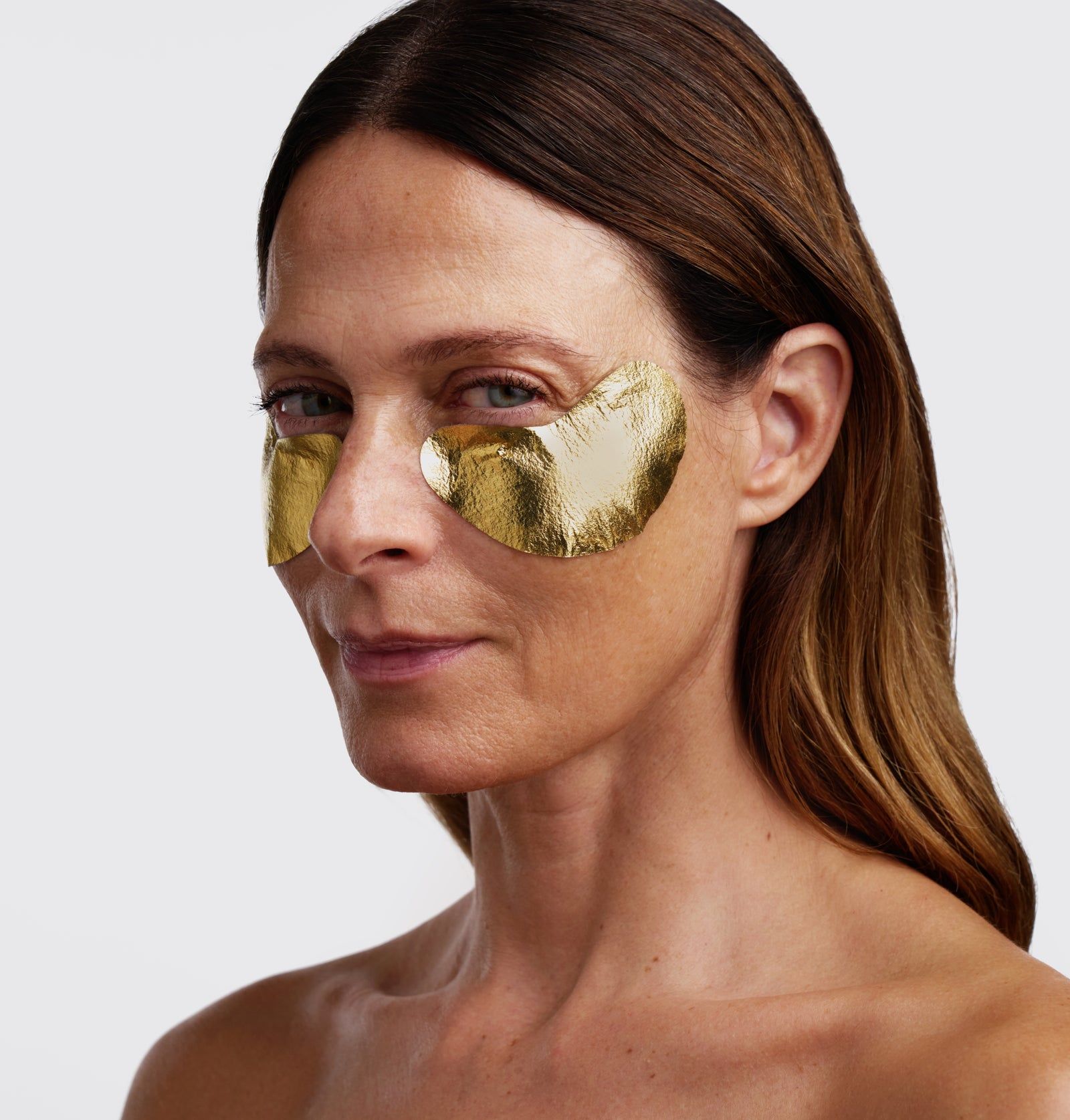 Frau mit goldenen Augenpads. Die Pads bedecken die Augenpartie. Nahaufnahme.