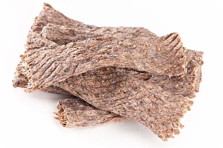 Getrocknetes Rehfleisch, in Streifen geschnitten. Helle, braune Farbe. Auf weißem Hintergrund.