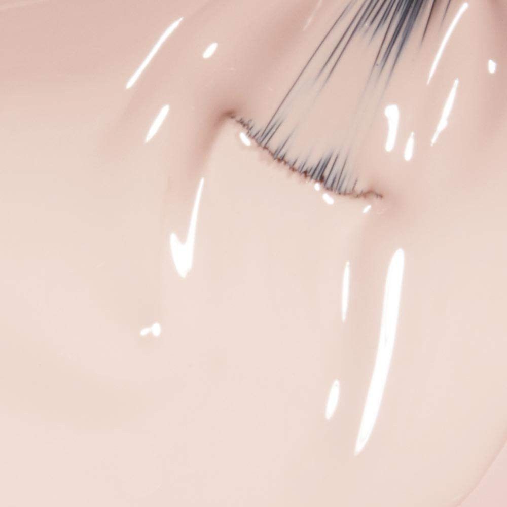 Nagellack-Applikator in hellem Farbton. Pinselspitze berührt die Oberfläche. Glänzende Textur mit Reflexionen.