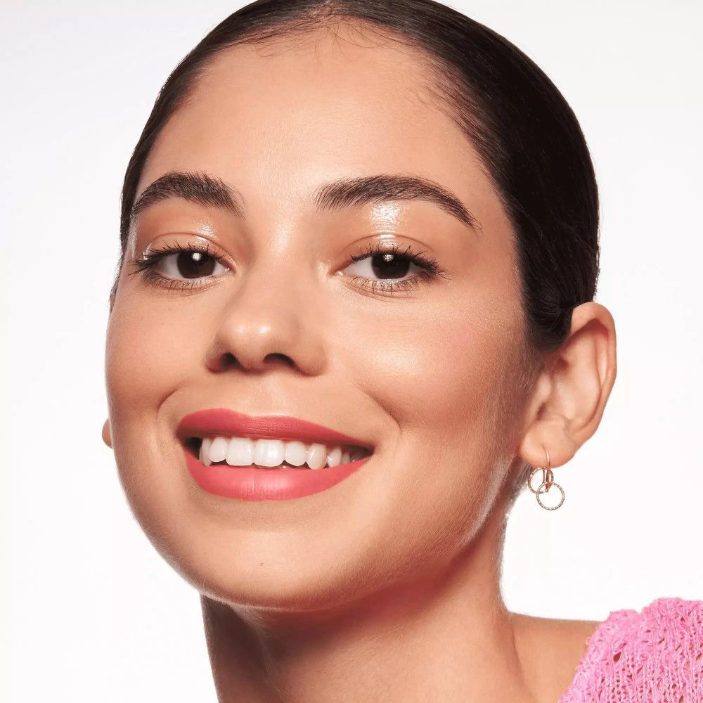 Porträt einer Frau mit rosa Lippenstift. Sie trägt Ohrringe.