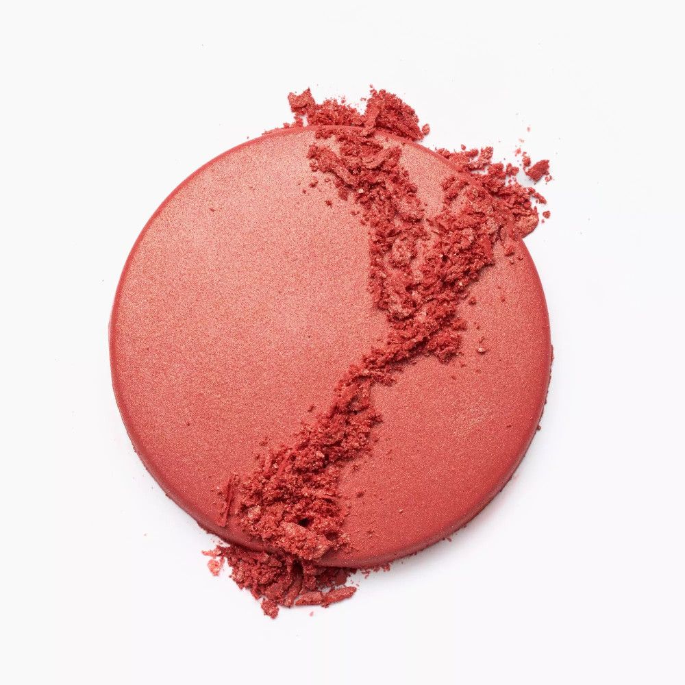 Runder, rosafarbener Rouge-Puder mit zerbröseltem Puder auf weißem Hintergrund.