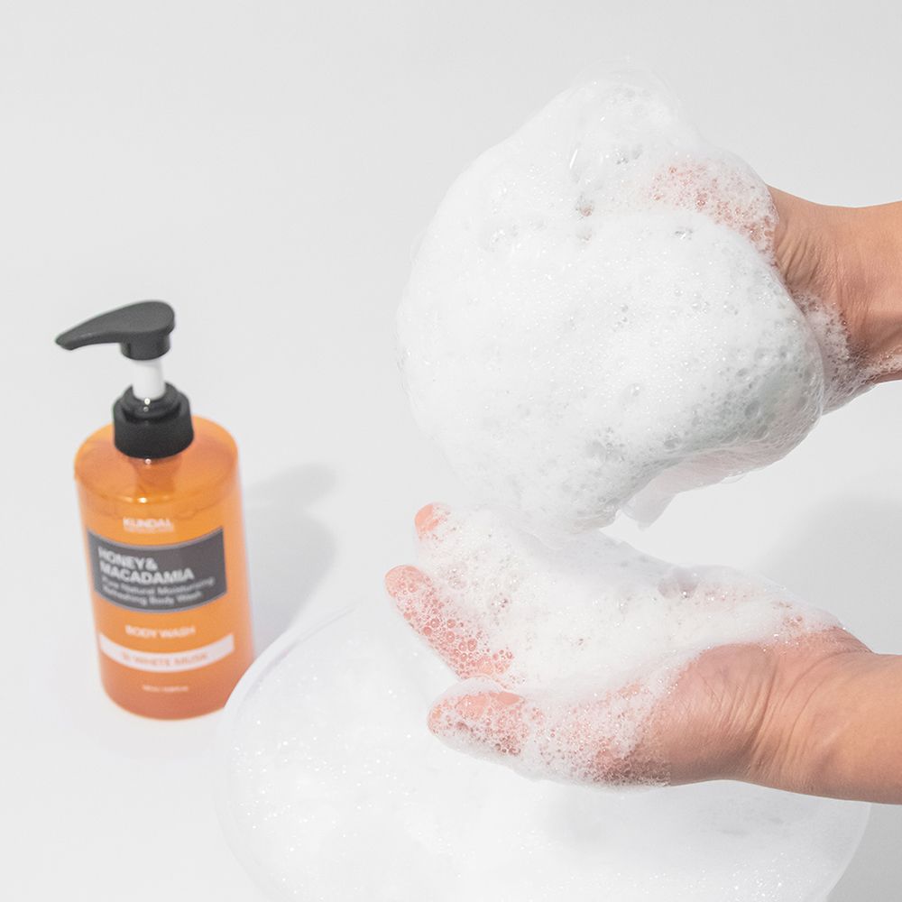 Hände halten Schaum. Eine KUNDAL-Flasche steht daneben. Ein Waschbecken ist im Hintergrund zu sehen.